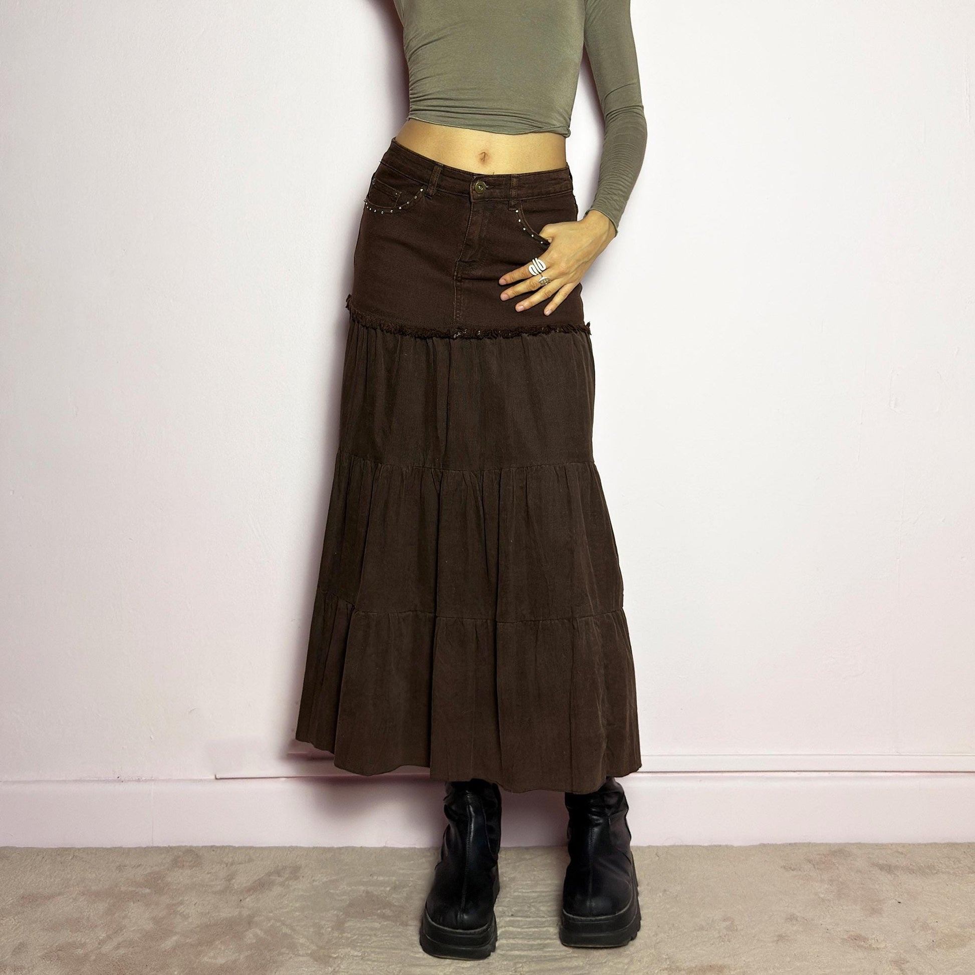 The Y2K Brown Tiered Midi Skirt is a vintage 2000s piece combining denim and soft corduroy for a unique mixed-fabric look. Featuring a stretchy waistband with rhinestone embellishments, pockets and a button-zipper closure, this skirt transitions into flowy tiered corduroy panels for a boho-inspired silhouette. Perfect for casual outfits. adult world shop