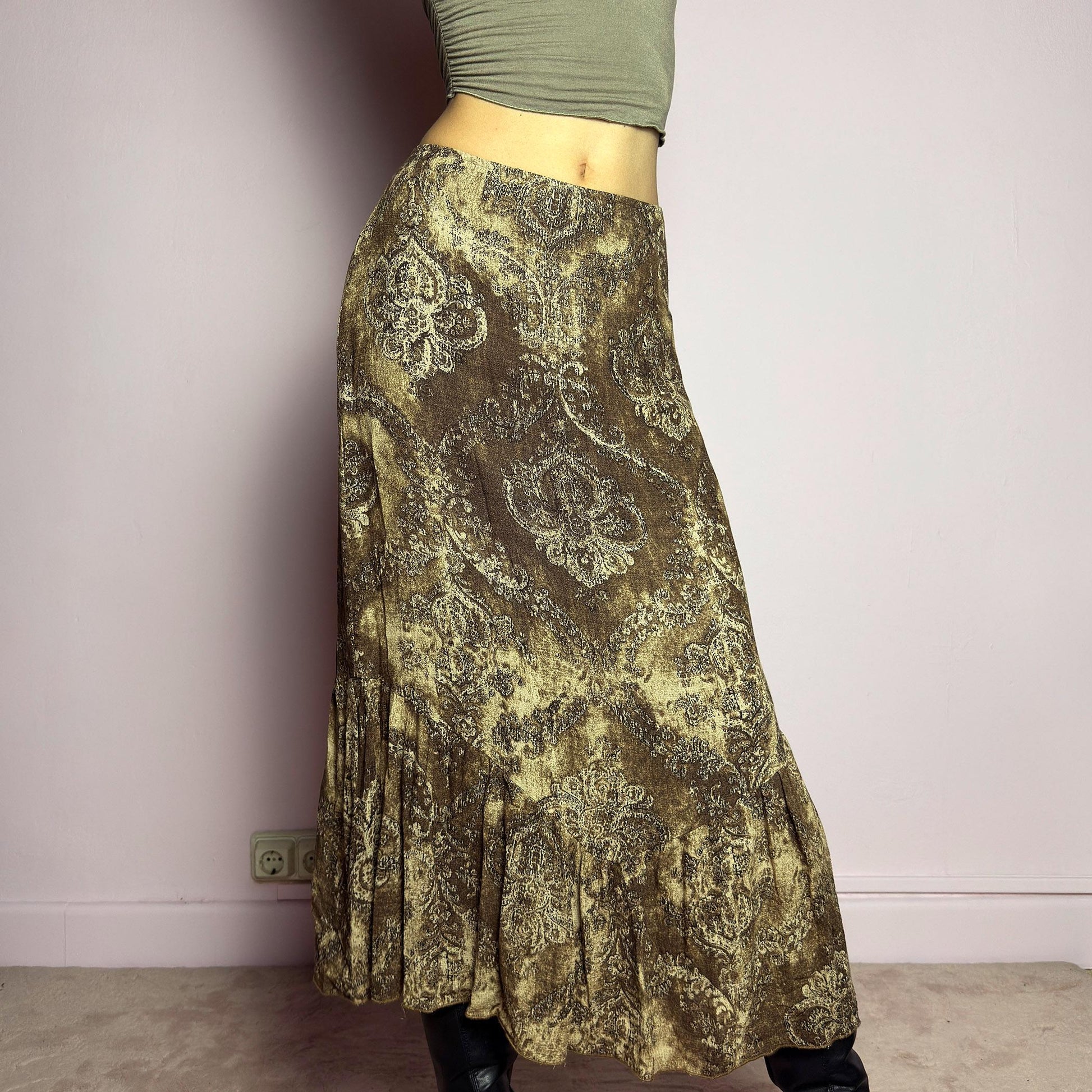 The Y2K Brown Paisley Midi Skirt is a vintage 2000s piece featuring a baroque-inspired paisley print. Designed with an earthy, whimsical aesthetic, this skirt has a flowy silhouette with subtle ruffle tiered details at the hem. It features a side zipper closure with an elastic waist. Perfect for grunge and bohemian-inspired outfits. adult world shop