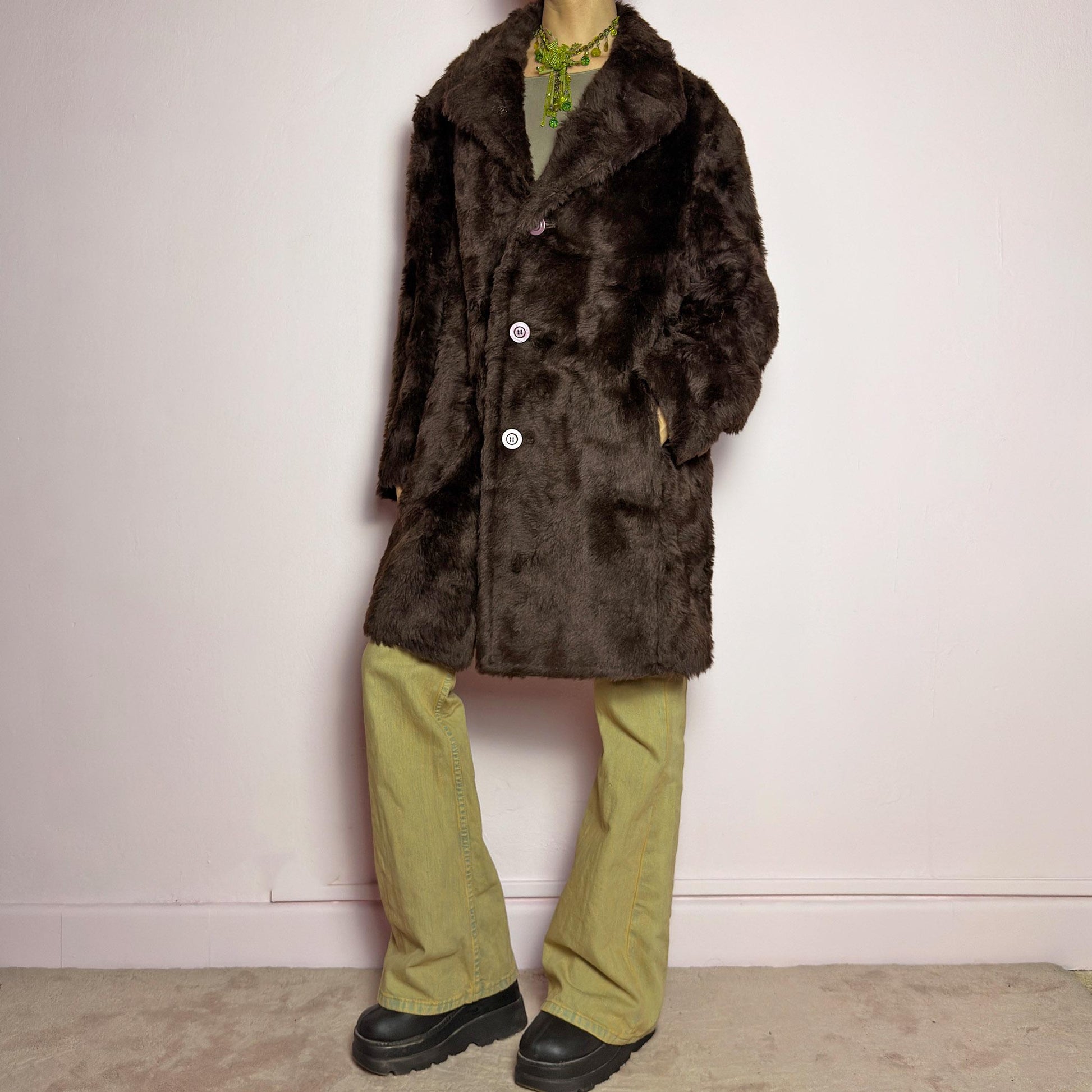 The Vintage 90s Faux Fur Brown Coat is a plush and cozy statement piece with a classic silhouette. Featuring deep chocolate brown faux fur fabric, a wide notched collar, bold contrasting buttons and pockets. Perfect for vintage streetwear, or cozy casual winter looks. adult world shop