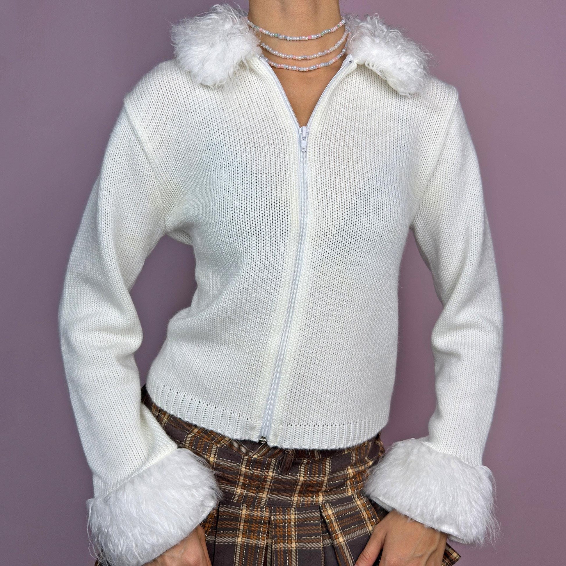 The Y2K White Fuzzy Trim Cardigan is a vintage 2000s piece featuring a soft knit fabric with faux fur details on the collar and cuffs. Designed with a zip-up front and a fitted silhouette, this cozy piece is perfect for layering in winter and for casual outfits. adult world shop