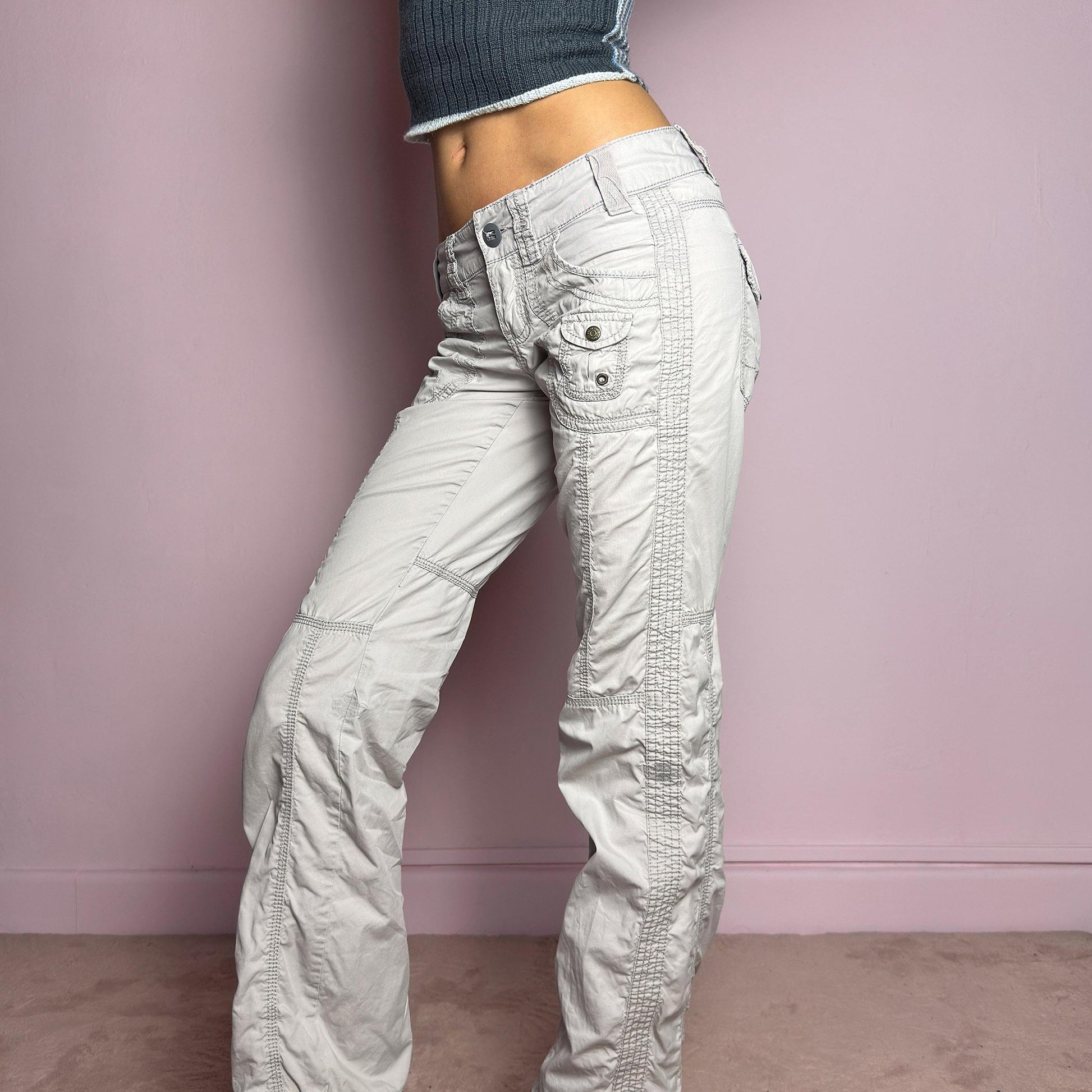 The Y2K Gray Low-Rise Pants are a vintage 2000s piece featuring a lightweight, structured fabric with a washed gray tone. Designed with a low-rise waist, button and zipper closure, and pockets, these pants offer a cropped, relaxed straight-leg fit with contrast stitching and panel detailing for a utilitarian-inspired aesthetic. Perfect for streetwear and casual grunge looks. adult world shop