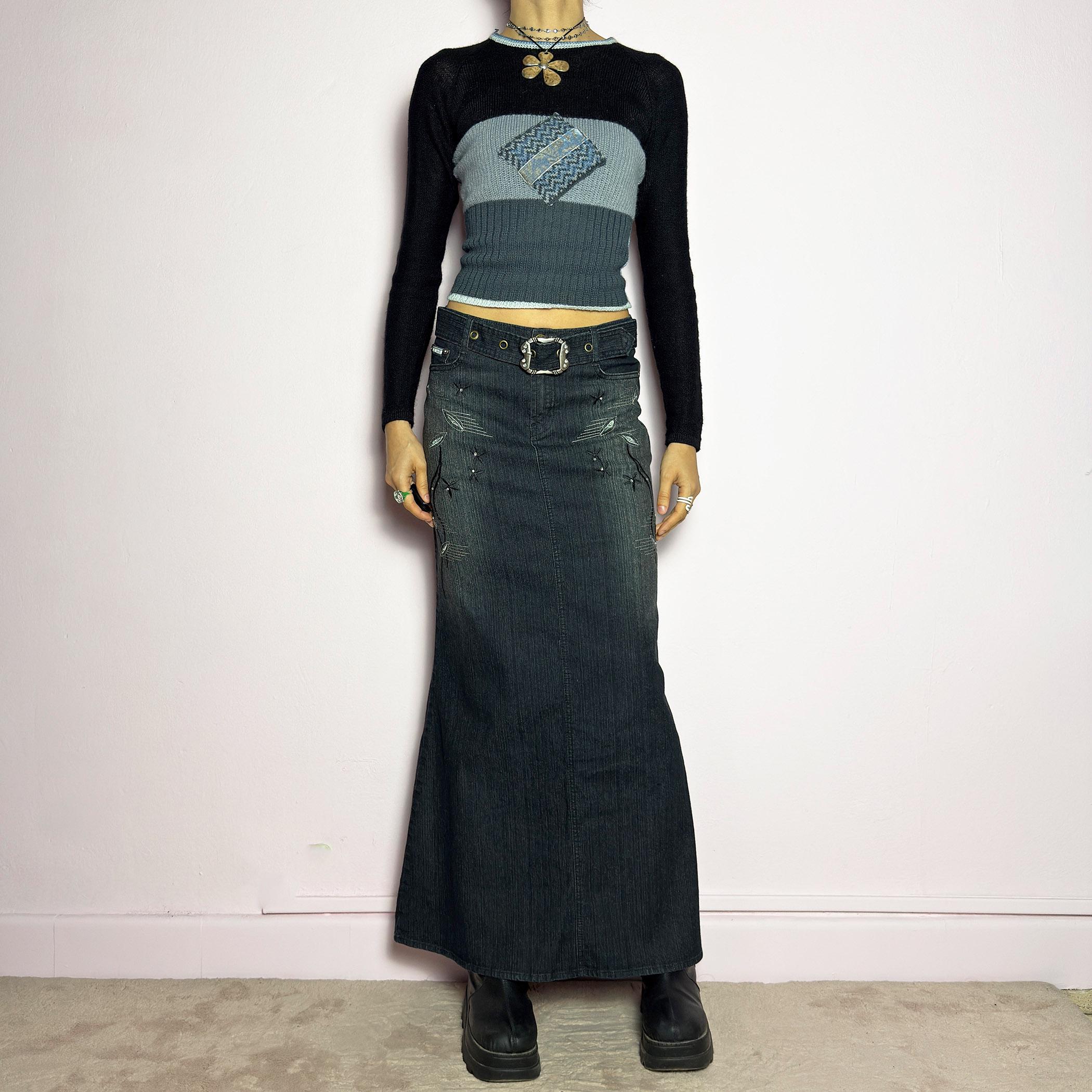 The Y2K Black Denim Maxi Skirt is a vintage 2000s piece featuring a sleek dark wash, rhinestone embellishments, and contrast stitching. Designed with a mid-rise fit and a stretchy denim fabric, it offers a structured silhouette that flares at the bottom. The skirt is finished with a button and zipper closure, pockets, and a removable belt for a customizable look. Perfect for casual streetwear outfits or an elegant night out. adult world shop