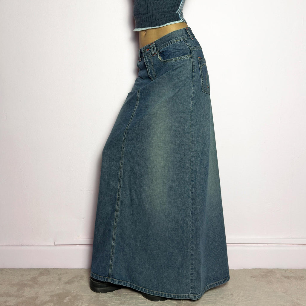 The Y2K Denim Maxi Skirt is a vintage 2000s essential featuring a structured denim fabric in a classic blue wash with subtle fading details. Designed with a mid-rise fit, button and zipper closure, and functional pockets, this skirt offers a sleek yet relaxed silhouette. The back slit adds ease of movement, making it perfect for casual everyday wear. adult world shop