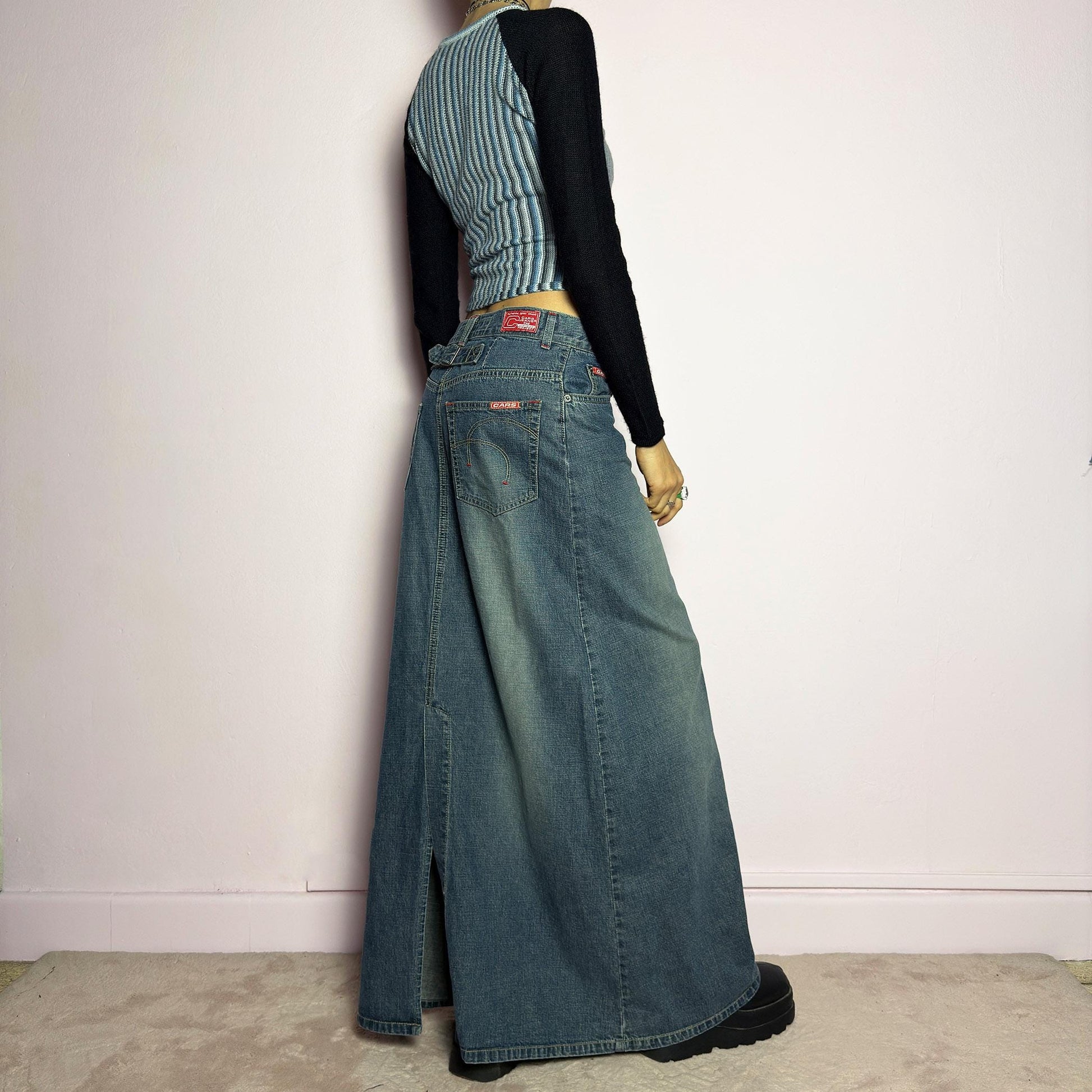 The Y2K Denim Maxi Skirt is a vintage 2000s essential featuring a structured denim fabric in a classic blue wash with subtle fading details. Designed with a mid-rise fit, button and zipper closure, and functional pockets, this skirt offers a sleek yet relaxed silhouette. The back slit adds ease of movement, making it perfect for casual everyday wear. adult world shop