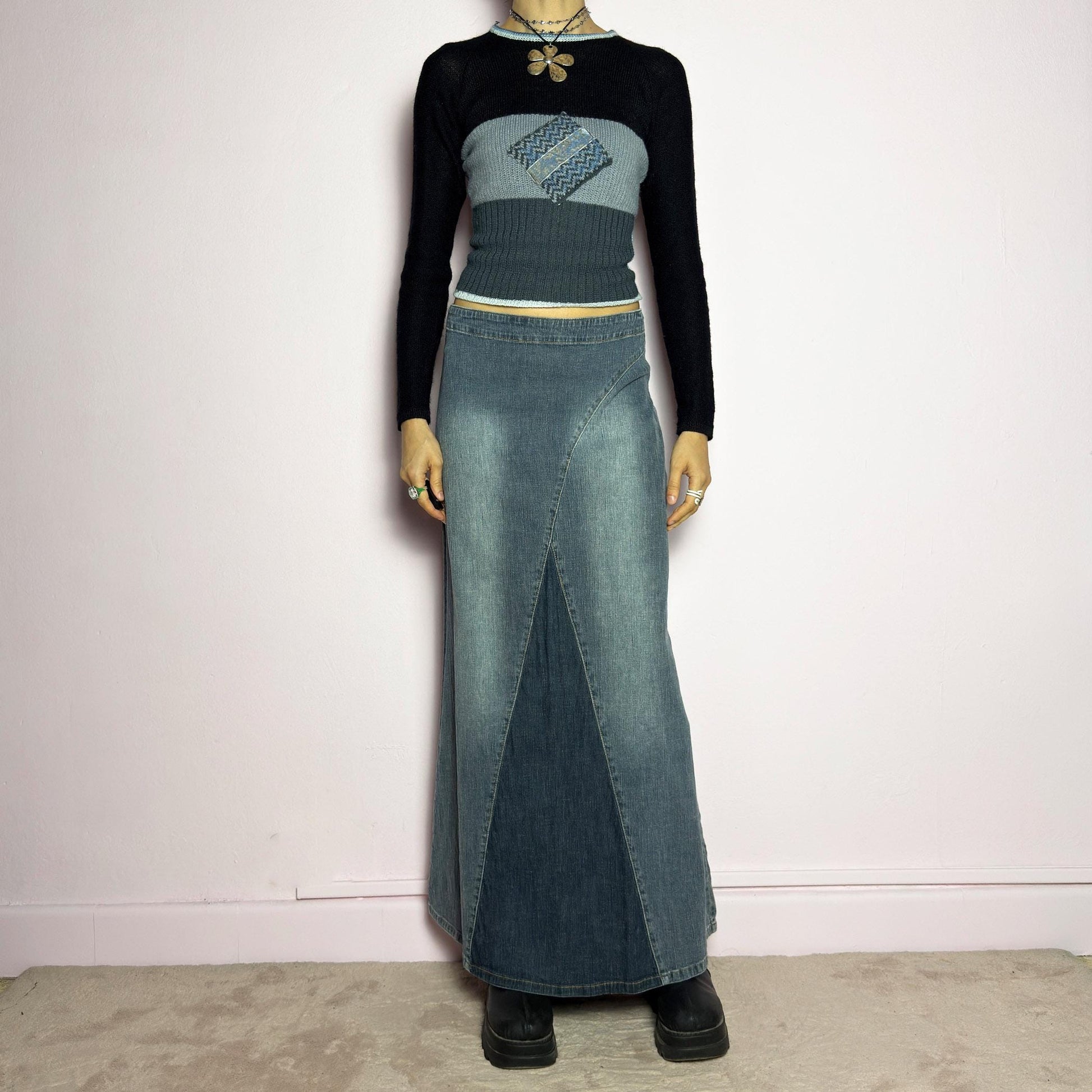 The Y2K Denim Paneled Maxi Skirt is a vintage 2000s piece featuring a unique paneled design with contrast wash details. Crafted from structured stretchy denim, this skirt offers a flattering mid-rise fit with a sleek, flared silhouette. Designed with a back zipper closure and a subtle back slit for ease of movement, it&#39;s perfect for casual streetwear outfits. adult world shop