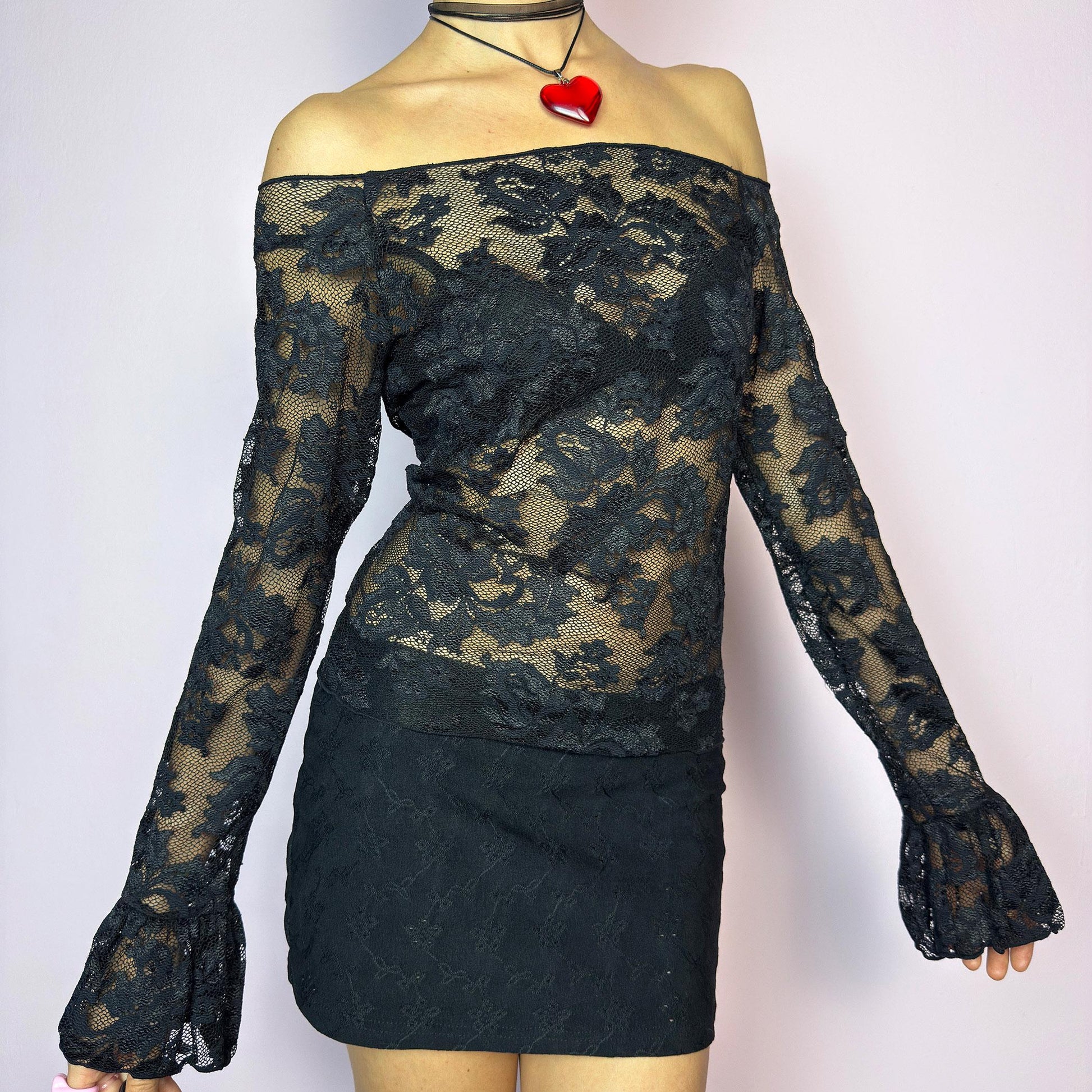 The Y2K Black Ruffle Lace Top is a vintage 2000s piece featuring a sheer mesh floral pattern with an off-the-shoulder neckline and dramatic ruffle bell sleeves. The fitted silhouette enhances its romantic and edgy vibe, making it ideal for layering or wearing on its own for a night-out look. Lightweight and breathable, perfect for summer styling. Made in Spain. Excellent vintage condition. adult world shop
