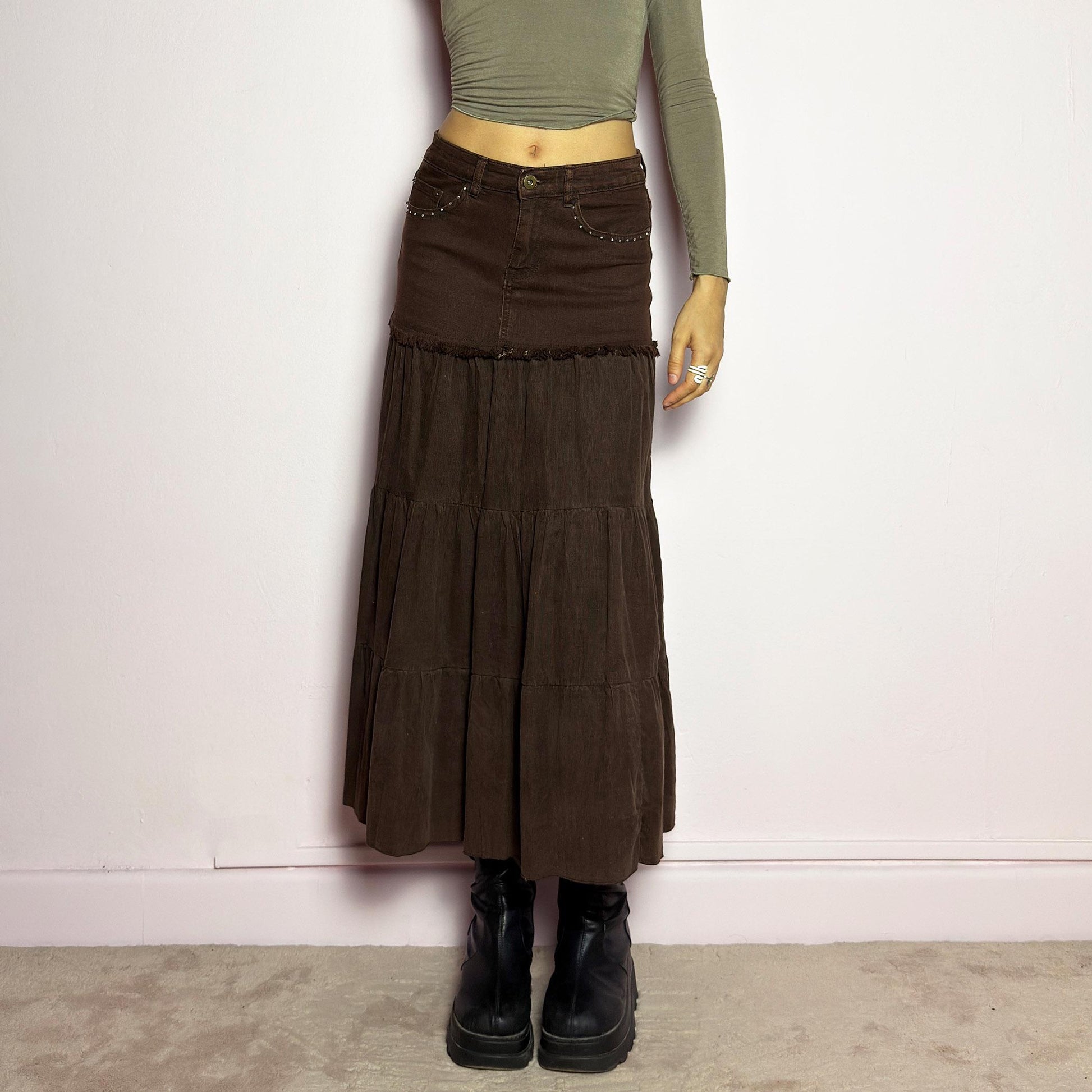 The Y2K Brown Tiered Midi Skirt is a vintage 2000s piece combining denim and soft corduroy for a unique mixed-fabric look. Featuring a stretchy waistband with rhinestone embellishments, pockets and a button-zipper closure, this skirt transitions into flowy tiered corduroy panels for a boho-inspired silhouette. Perfect for casual outfits. adult world shop