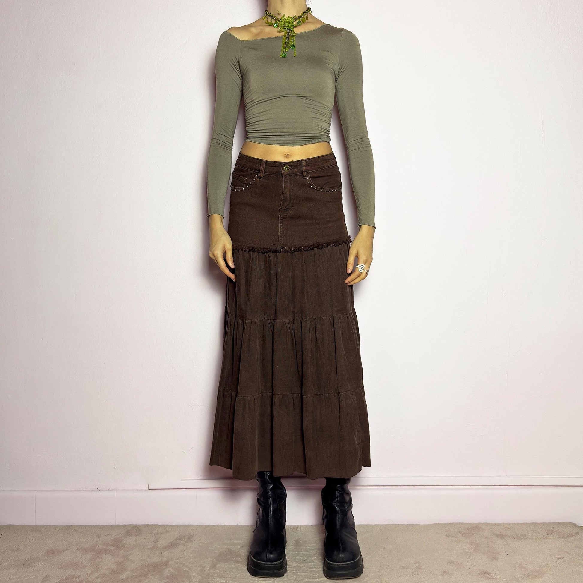 The Y2K Brown Tiered Midi Skirt is a vintage 2000s piece combining denim and soft corduroy for a unique mixed-fabric look. Featuring a stretchy waistband with rhinestone embellishments, pockets and a button-zipper closure, this skirt transitions into flowy tiered corduroy panels for a boho-inspired silhouette. Perfect for casual outfits. adult world shop