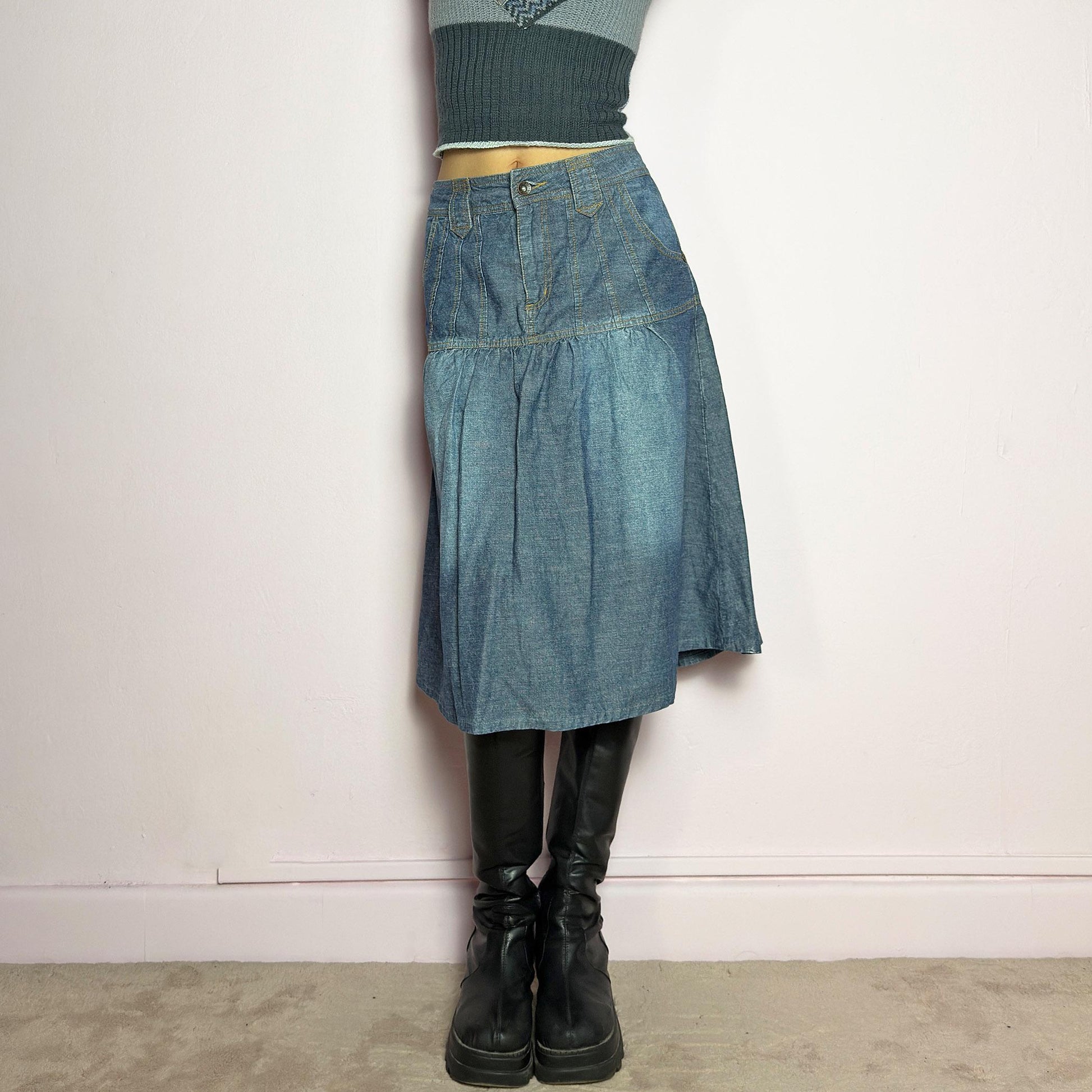 The Y2K Flare Denim Midi Skirt is a vintage 2000s piece featuring a unique panel construction with contrast stitching and a gathered hem for a flared silhouette. Designed with a mid-rise fit, button and zipper closure, and pockets. Perfect for effortless streetwear and everyday outfits.