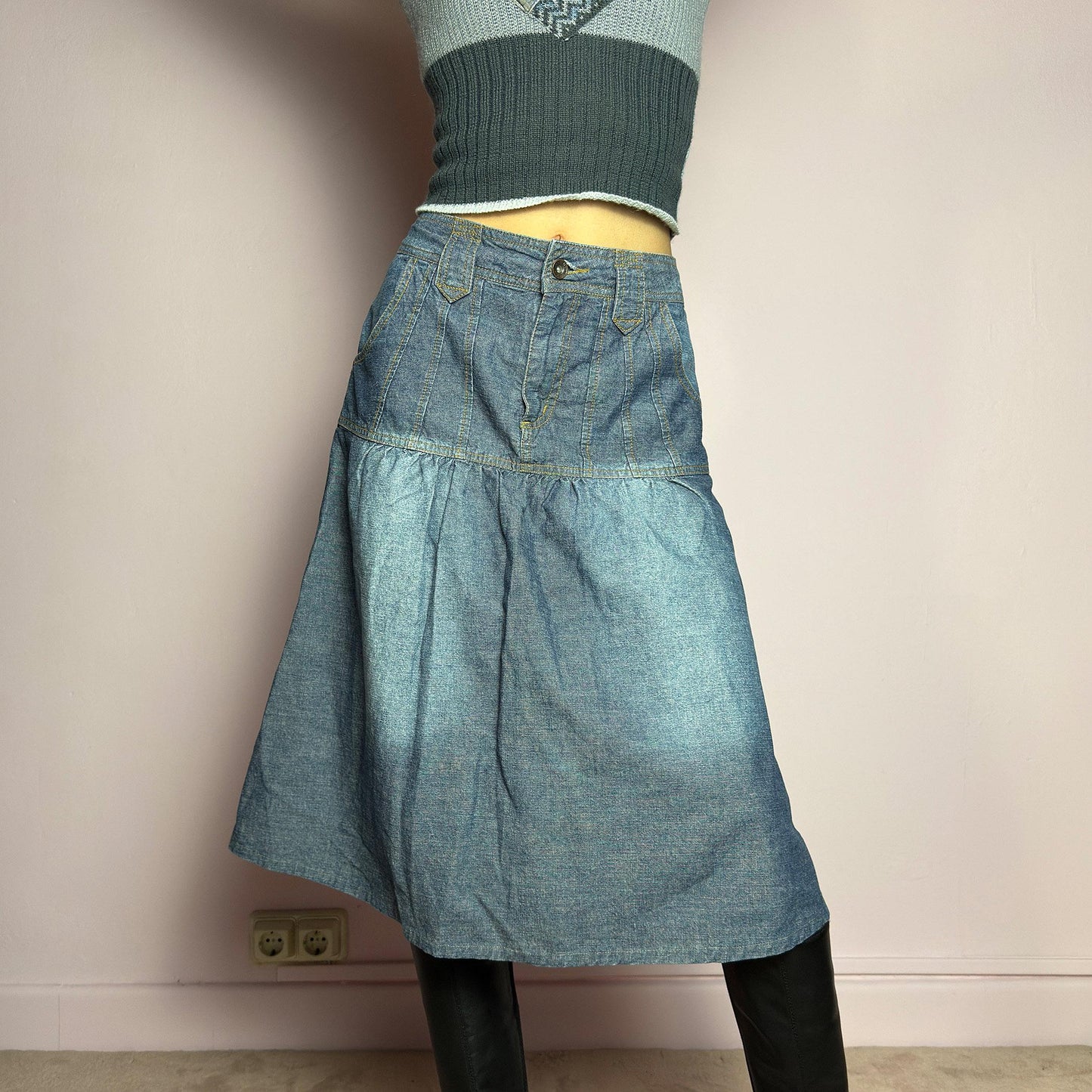 The Y2K Flare Denim Midi Skirt is a vintage 2000s piece featuring a unique panel construction with contrast stitching and a gathered hem for a flared silhouette. Designed with a mid-rise fit, button and zipper closure, and pockets. Perfect for effortless streetwear and everyday outfits.