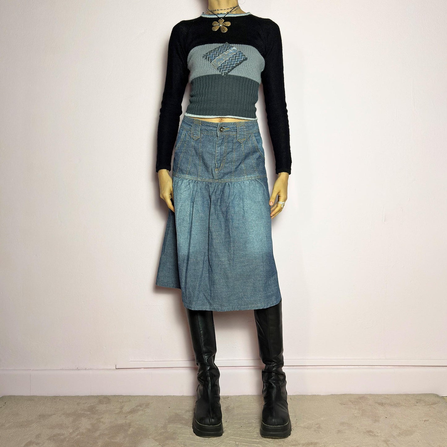 The Y2K Flare Denim Midi Skirt is a vintage 2000s piece featuring a unique panel construction with contrast stitching and a gathered hem for a flared silhouette. Designed with a mid-rise fit, button and zipper closure, and pockets. Perfect for effortless streetwear and everyday outfits.