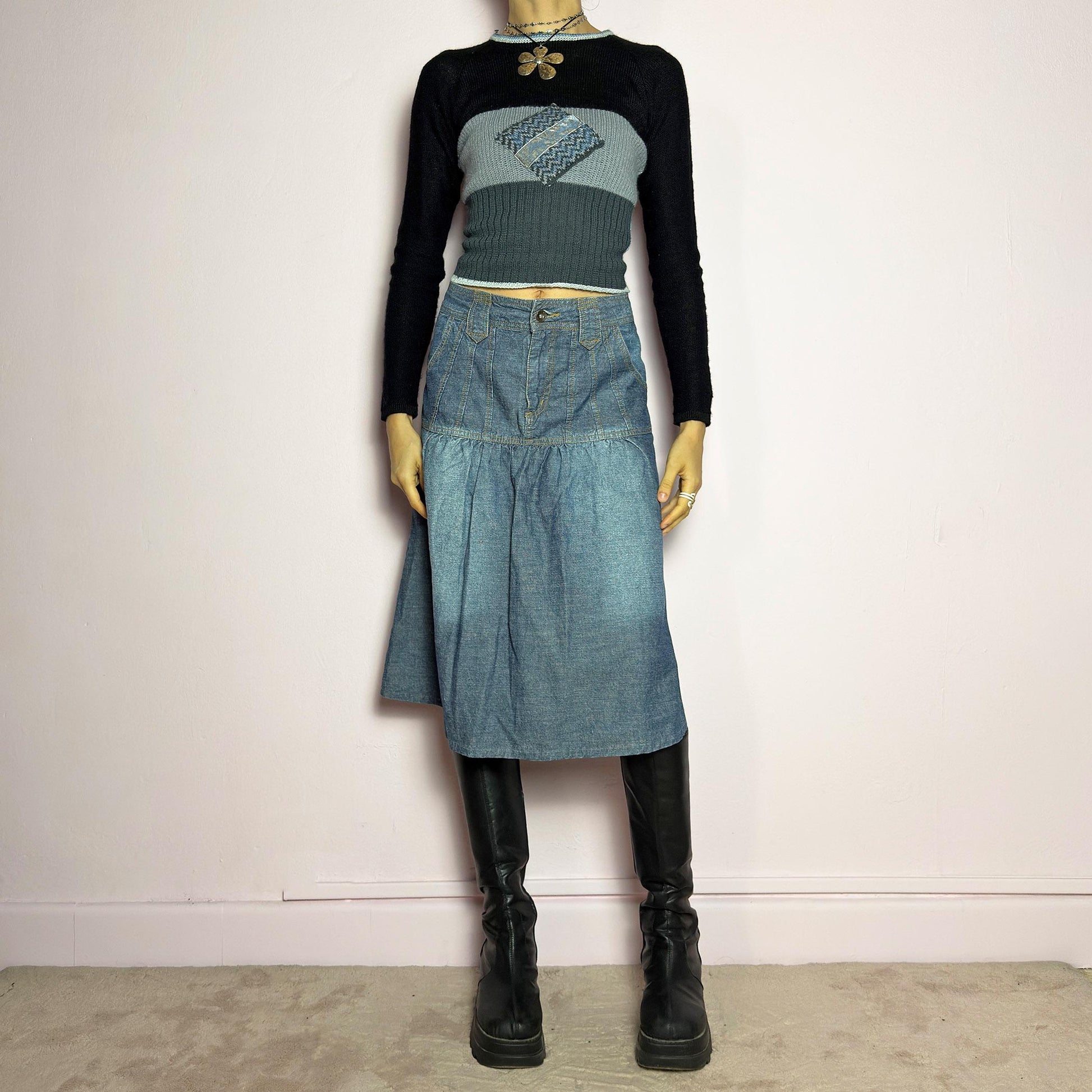 The Y2K Flare Denim Midi Skirt is a vintage 2000s piece featuring a unique panel construction with contrast stitching and a gathered hem for a flared silhouette. Designed with a mid-rise fit, button and zipper closure, and pockets. Perfect for effortless streetwear and everyday outfits.