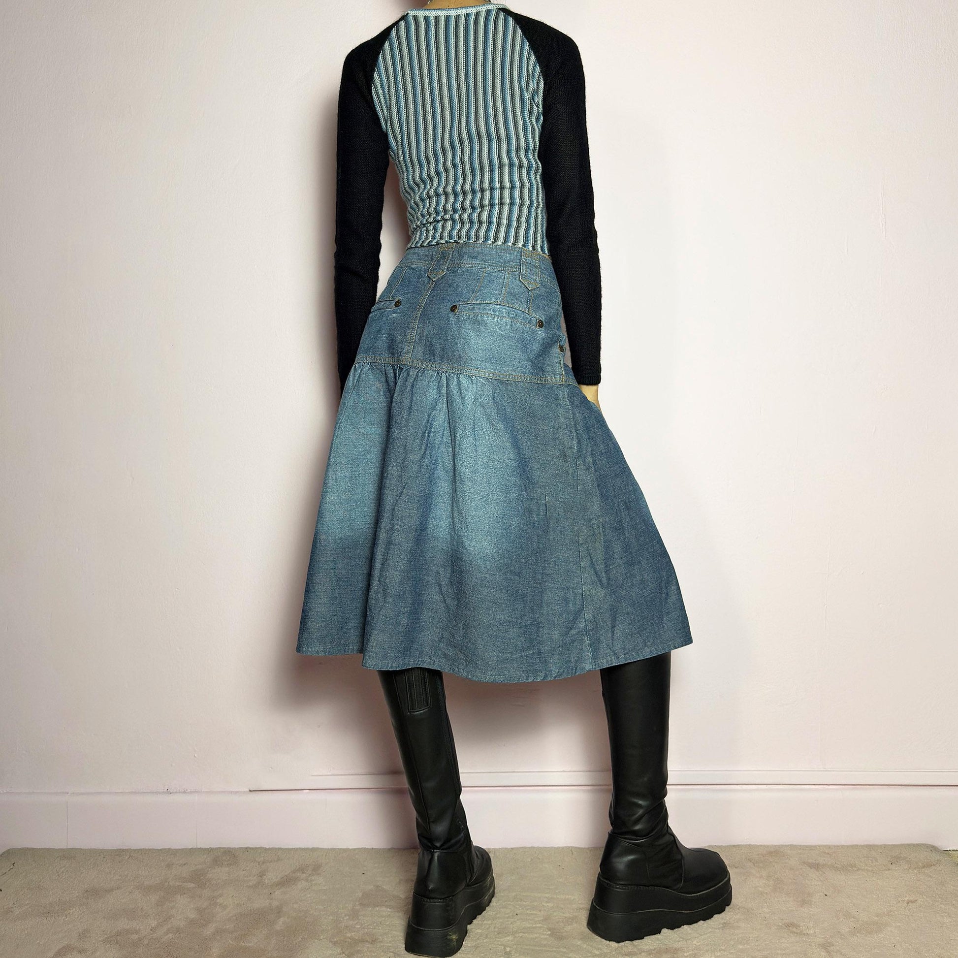 The Y2K Flare Denim Midi Skirt is a vintage 2000s piece featuring a unique panel construction with contrast stitching and a gathered hem for a flared silhouette. Designed with a mid-rise fit, button and zipper closure, and pockets. Perfect for effortless streetwear and everyday outfits.