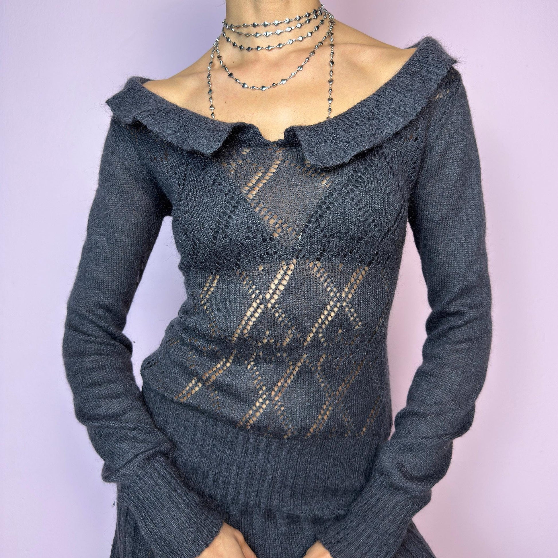 The Y2K Gray Mini Knit Dress is a vintage 2000s piece featuring a ruffled off-shoulder neckline and sheer diamond-knit pattern through the bodice. The fitted waist flows into a pleated mini skirt. Made from a soft, stretchy knit that hugs the body while remaining comfortable. Perfect for casual autumn look. adult world shop