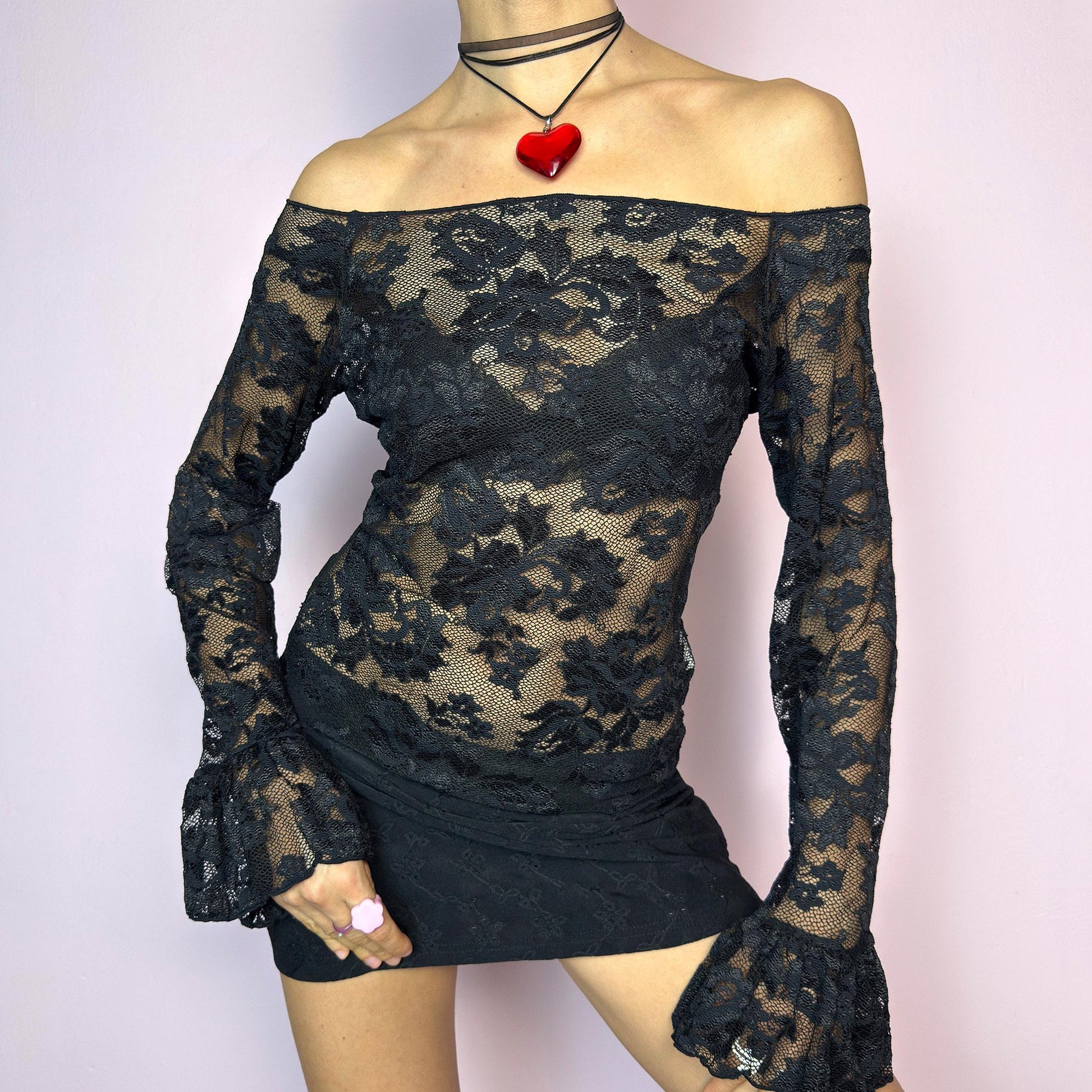 The Y2K Black Ruffle Lace Top is a vintage 2000s piece featuring a sheer mesh floral pattern with an off-the-shoulder neckline and dramatic ruffle bell sleeves. The fitted silhouette enhances its romantic and edgy vibe, making it ideal for layering or wearing on its own for a night-out look. Lightweight and breathable, perfect for summer styling. Made in Spain. Excellent vintage condition. adult world shop