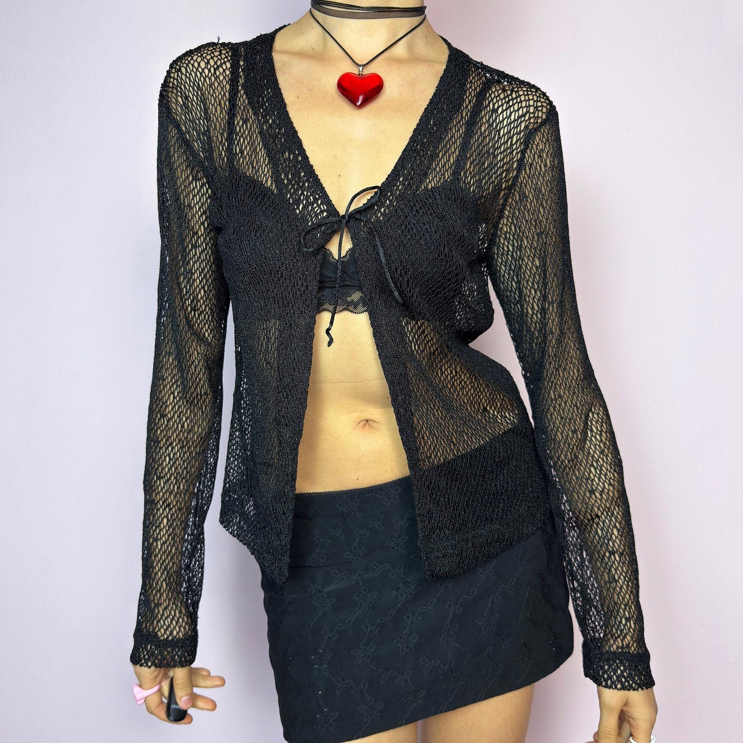 The Y2K Black Sheer Tie Top is a vintage 2000s sheer tie-front top in a bold black fishnet knit. Features a breathable, lightweight mesh texture with long sleeves and a single front tie for an adjustable fit. The open weave adds an edgy, see-through effect — ideal for layering. A perfect festival piece and summer staple. Great vintage condition. adult world shop