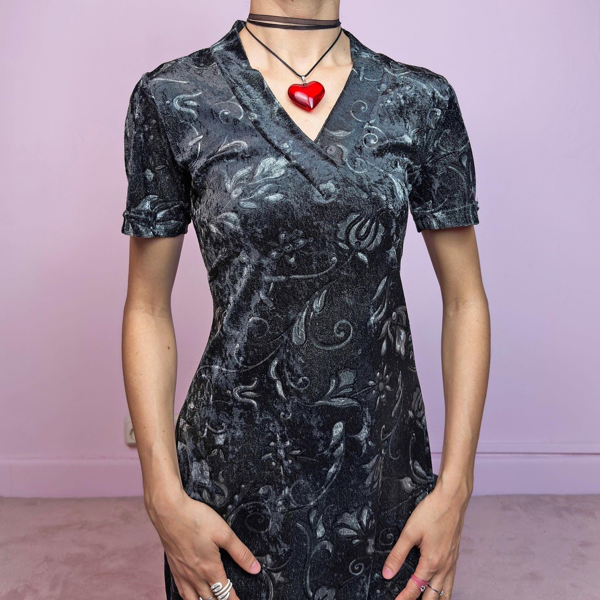 The Vintage 90s Gray Velvet Midi Dress is a moody and elegant 90s piece made from soft, stretchy dark gray velvet with a baroque-style printed pattern. Features a flattering V-neckline, short sleeves, and a sleek longline silhouette. The velvety fabric gives it a luxurious feel while staying comfy. Perfect for witchy aesthetics, gothic romance, or vintage night-out looks.