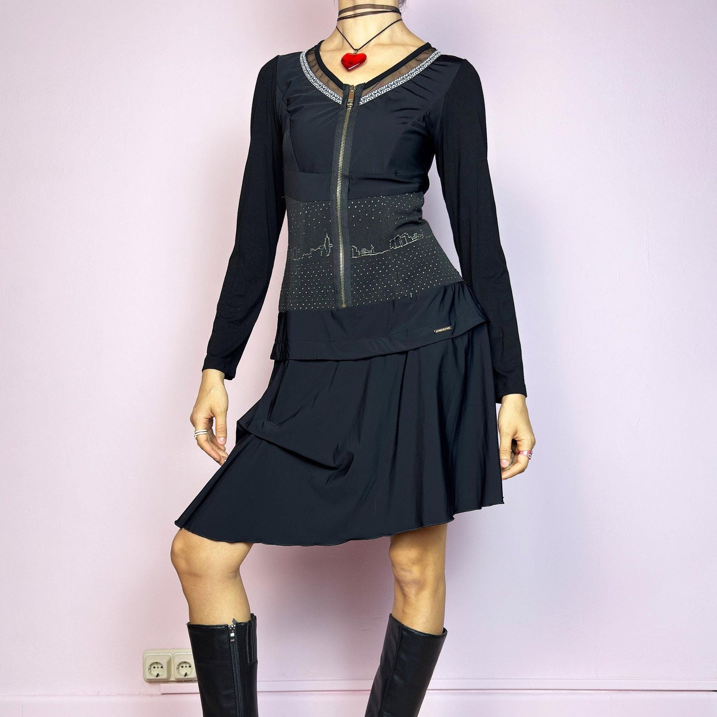 The Y2K Black Long Sleeve Mini Dress is a vintage 2000s sleek and deconstructed mini dress featuring a fitted bodice with a front zipper and a glittery cityscape detail at the waist. The long sleeves balance the edgy vibe of the layered, asymmetrical skirt, giving it a sculptural silhouette. Stretchy and comfortable, this dress is perfect for cybercore and futuristic clubwear. Great vintage condition.