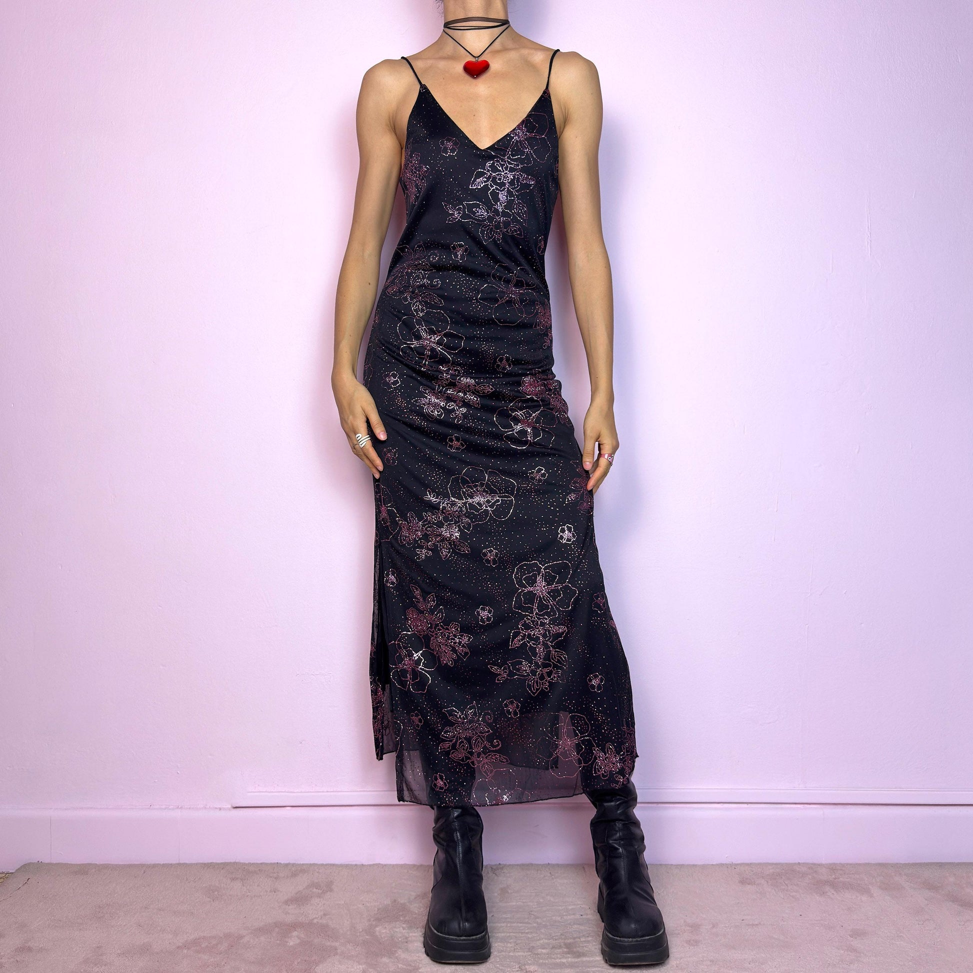 The Y2K Black Glitter Midi Dress is a rare 2000s dress featuring a delicate pink glitter floral pattern on a sheer black mesh overlay with a soft lining beneath. This midi-length piece includes skinny spaghetti straps, a deep V neckline, and a side slits for added movement. The open lace-up back detail gives it a sultry edge, perfect for night outs, alt party looks, or romantic goth aesthetics. Fitted silhouette with a flattering drape. Made in France. Excellent vintage condition.