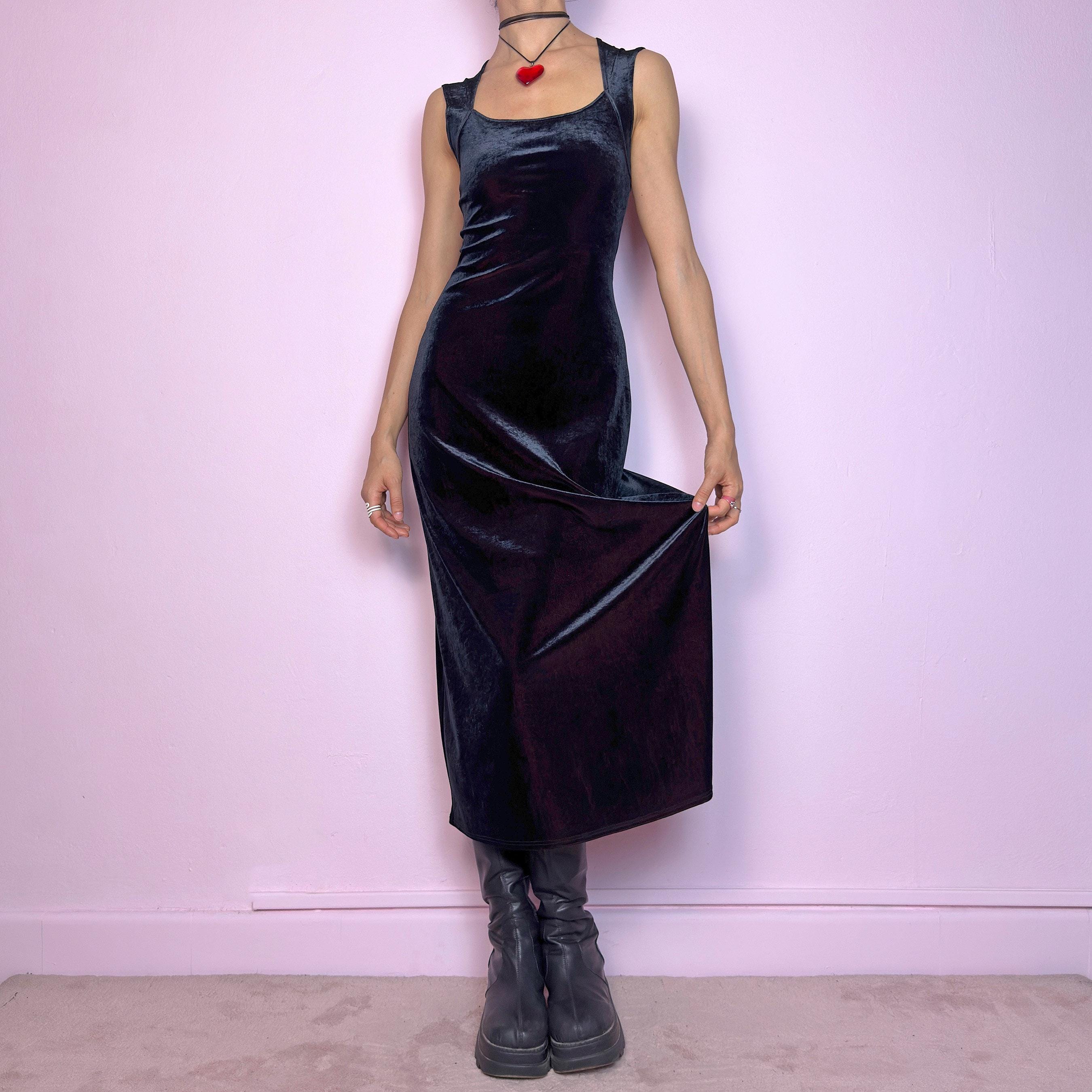 The Vintage 90s Black Velvet Midi Dress is pure elegance with a twist. Crafted from deep black velvet with a maroon undertone, it catches the light with rich, dark burgundy reflections that give it a luxe finish. Features wide straps, a square neckline, and a body-hugging midi silhouette that flatters and elongates. Soft and stretchy for comfort, yet bold and dramatic for gothic, romantic, or night-out looks. A subtly striking piece that stands out in movement and moonlight.