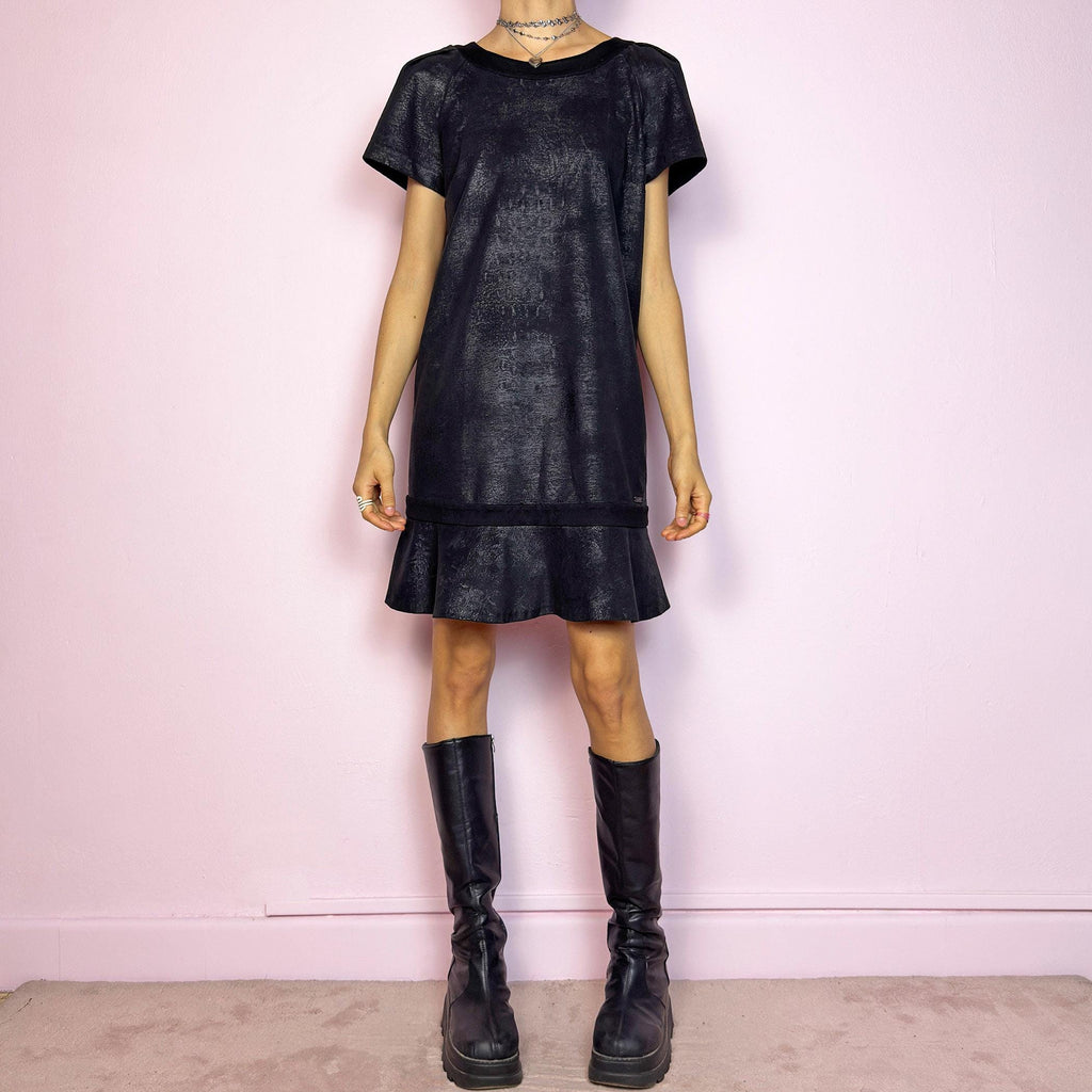 The Y2K Black Cop Copine Dress is a sleek and structured mini dress with subtle futuristic flair. Made from a soft black fabric with a slight sheen and textured abstract finish, it features short sleeves, a relaxed straight silhouette, and a ruffled hem for added movement. The back showcases a bold V-cut detail with a button closure at the neck. Unique yet minimalist, perfect for modern grunge or avant-garde looks. Made in Portugal. Excellent vintage condition.