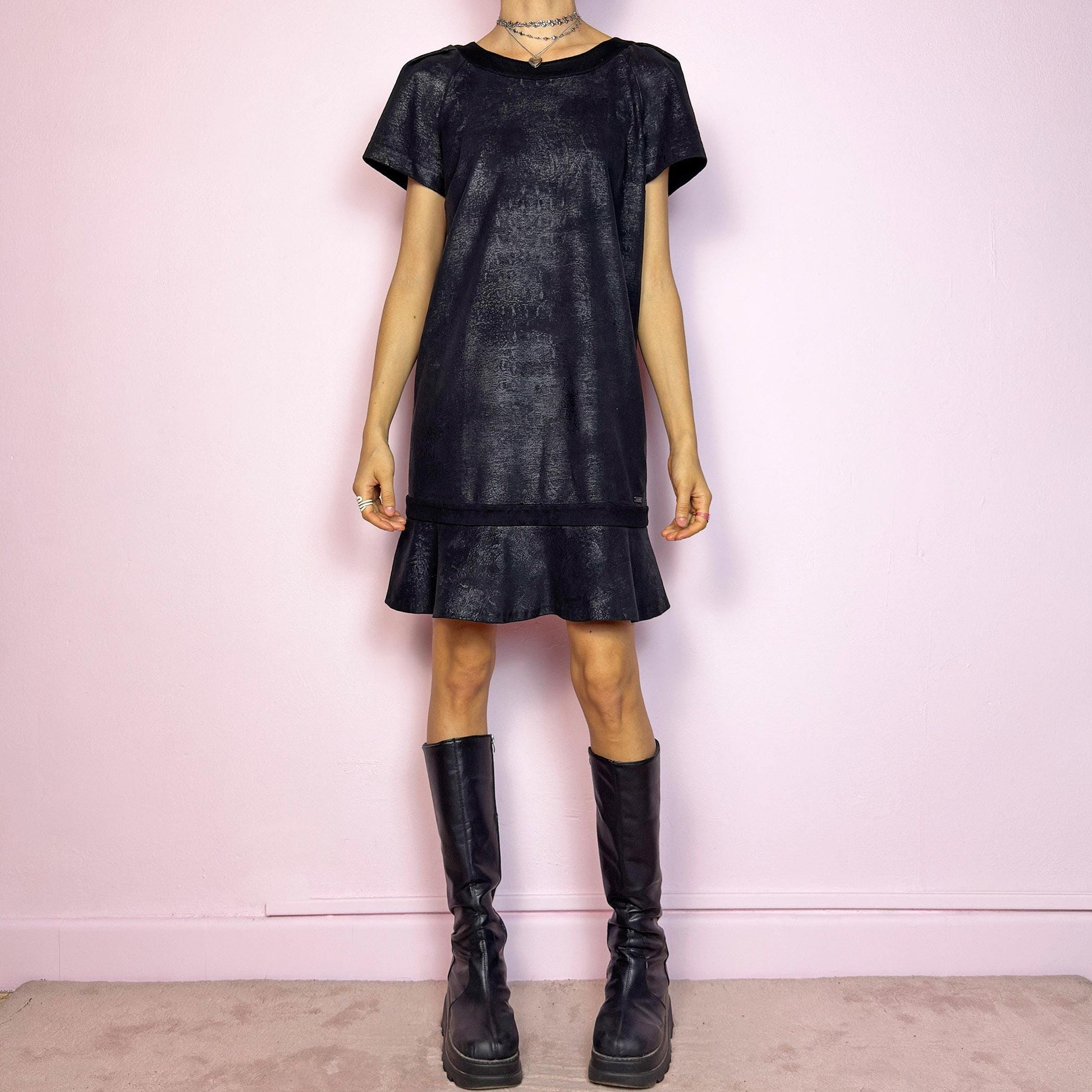 The Y2K Black Cop Copine Dress is a sleek and structured mini dress with subtle futuristic flair. Made from a soft black fabric with a slight sheen and textured abstract finish, it features short sleeves, a relaxed straight silhouette, and a ruffled hem for added movement. The back showcases a bold V-cut detail with a button closure at the neck. Unique yet minimalist, perfect for modern grunge or avant-garde looks. Made in Portugal. Excellent vintage condition.