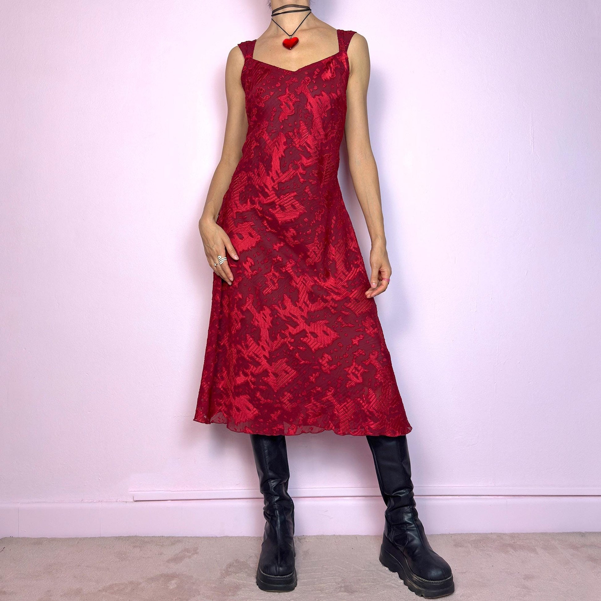 The Vintage 90s Maroon Textured Midi Dress is a romantic and striking piece in a rich maroon tone with abstract textured patterns and a sheer overlay. Designed with wide straps, a flattering sweetheart neckline, and a flowy midi-length cut. The semi-sheer fabric adds depth while the inner lining provides comfort. Perfect for formal events, romantic nights, or gothic glam looks. Elegant, timeless, and effortlessly dramatic. Excellent vintage condition.