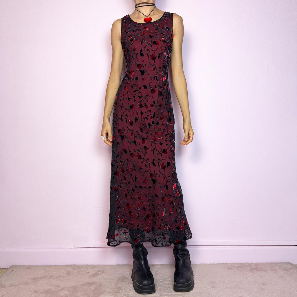 The Vintage 90s Black Sheer Floral Midi Dress is a striking piece featuring a sheer black overlay with textured velvet floral details layered over a vibrant red lining. The sleeveless design and round neckline offer a timeless silhouette, while the fitted shape and midi length create a flattering, romantic look. The fabric is slightly stretchy and flowy, with a gothic romantic vibe perfect for dark fairycore, witchy looks, or 2000s party aesthetics. Excellent vintage condition.