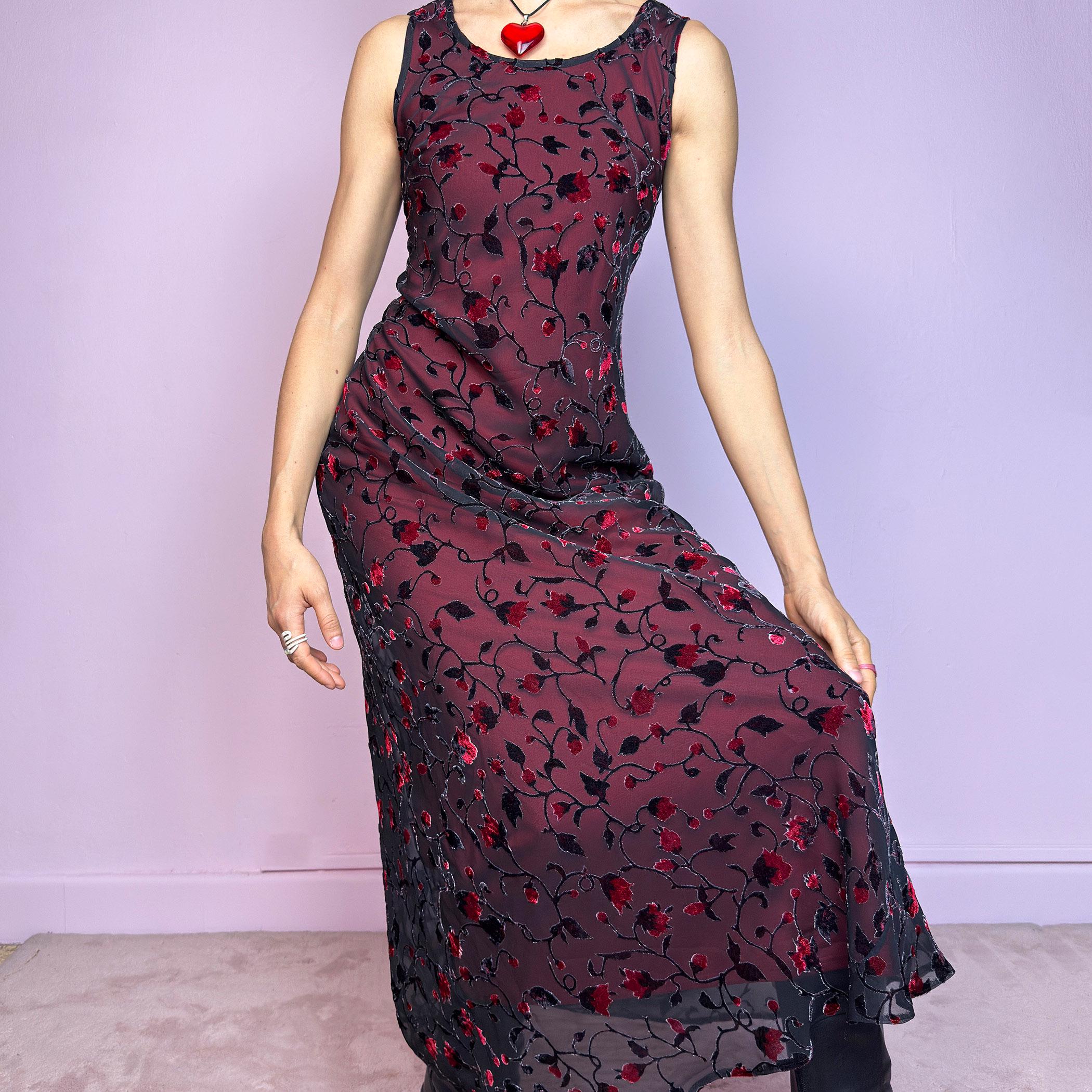 The Vintage 90s Black Sheer Floral Midi Dress is a striking piece featuring a sheer black overlay with textured velvet floral details layered over a vibrant red lining. The sleeveless design and round neckline offer a timeless silhouette, while the fitted shape and midi length create a flattering, romantic look. The fabric is slightly stretchy and flowy, with a gothic romantic vibe perfect for dark fairycore, witchy looks, or 2000s party aesthetics. Excellent vintage condition.