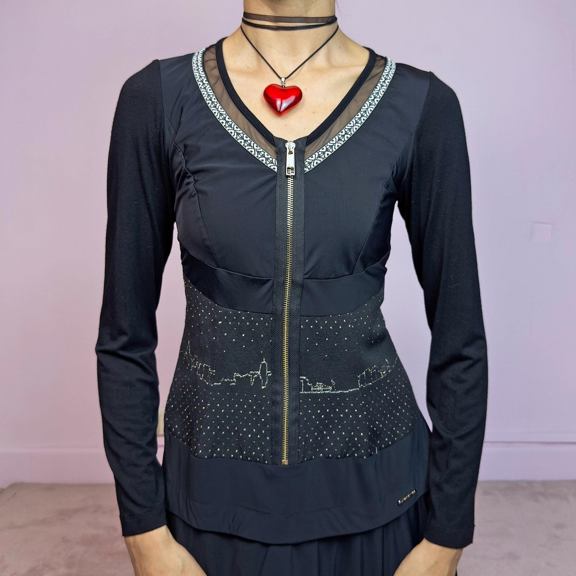 The Y2K Black Long Sleeve Mini Dress is a vintage 2000s sleek and deconstructed mini dress featuring a fitted bodice with a front zipper and a glittery cityscape detail at the waist. The long sleeves balance the edgy vibe of the layered, asymmetrical skirt, giving it a sculptural silhouette. Stretchy and comfortable, this dress is perfect for cybercore and futuristic clubwear. Great vintage condition.