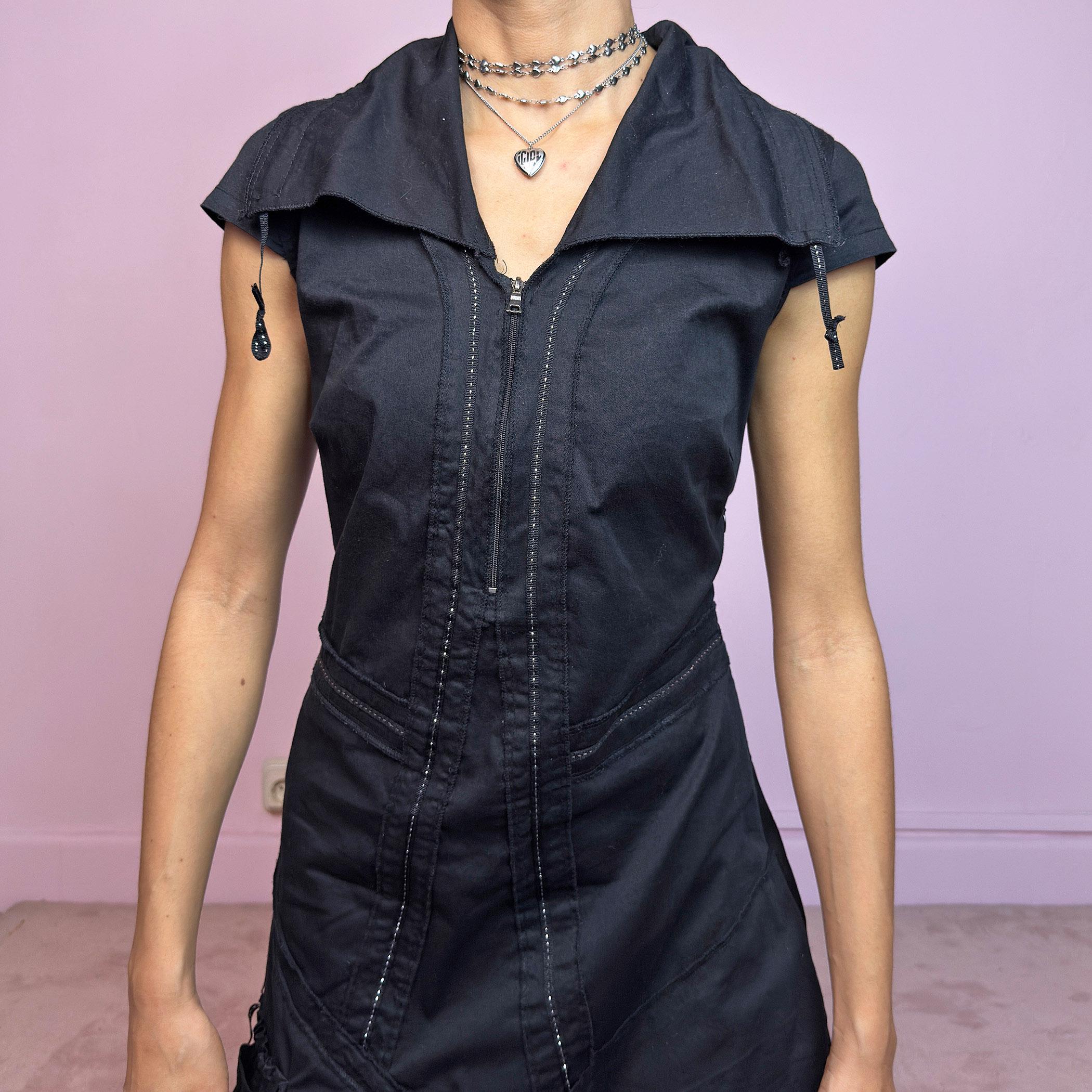 This vintage 2000s black techwear dress features cap sleeves, a dramatic asymmetric hem, and sculptural paneling for a bold silhouette. Made from a stretchy fabric, it includes a side zip closure and ruched utility pocket. Decorative topstitching and a funnel-style collar with drawstrings elevate the structure. Mid-length and lightweight, perfect for summer. A sleek statement in futuristic edge. Great vintage condition.