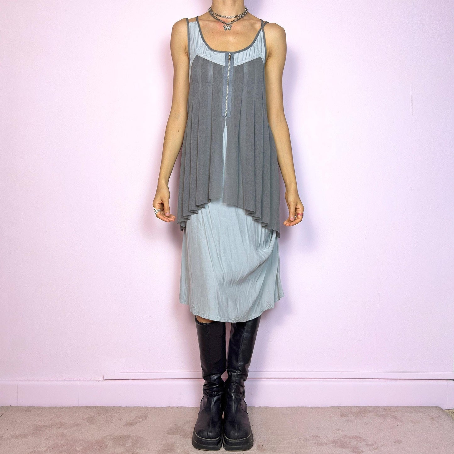 This vintage 2000s midi dress features layered grey tones in mixed textures, including a pleated mesh overlay with faux front zip detail and a side zipper closure. The sleeveless cut and flared asymmetric drape create sculptural movement. Falls below the knee, lightweight, with no stretch. A deconstructed Y2K silhouette—futuristic, quiet, and avant-garde. Perfect for summer days or experimental night looks. Excellent vintage condition.