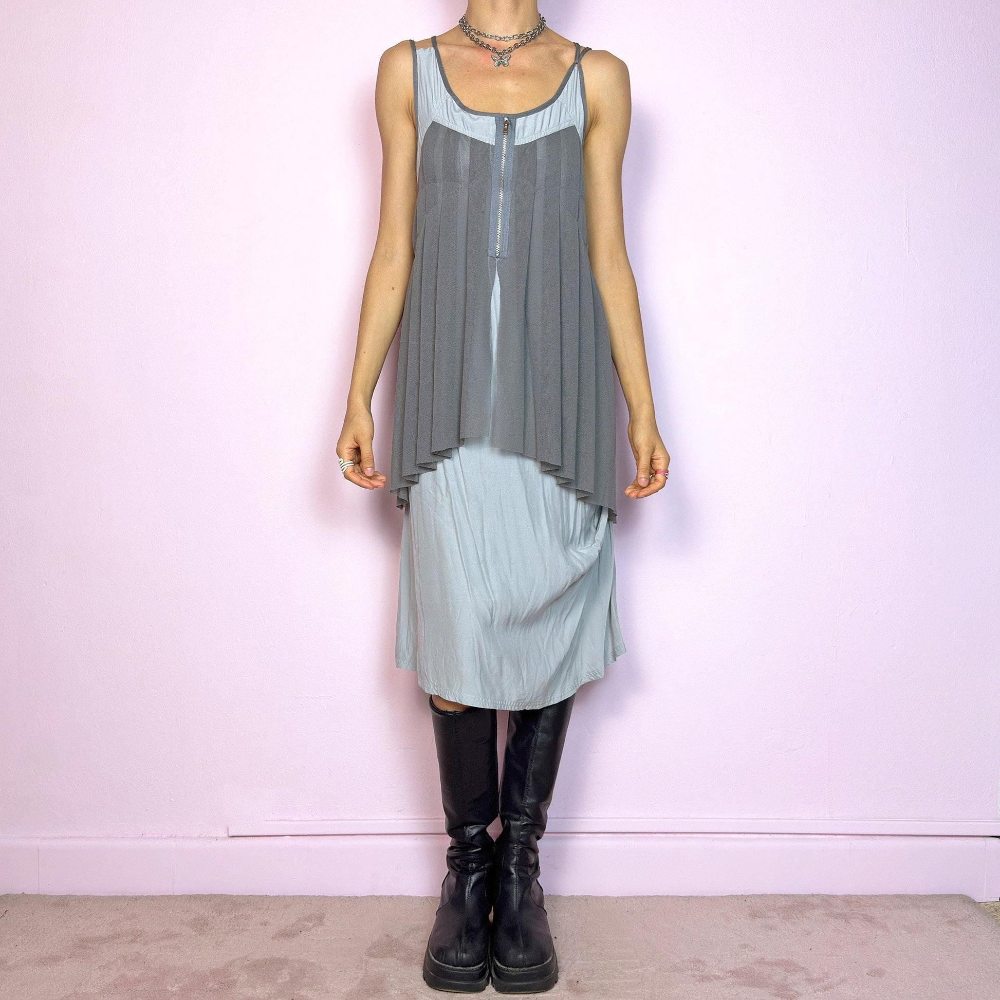 This vintage 2000s midi dress features layered grey tones in mixed textures, including a pleated mesh overlay with faux front zip detail and a side zipper closure. The sleeveless cut and flared asymmetric drape create sculptural movement. Falls below the knee, lightweight, with no stretch. A deconstructed Y2K silhouette—futuristic, quiet, and avant-garde. Perfect for summer days or experimental night looks. Excellent vintage condition.
