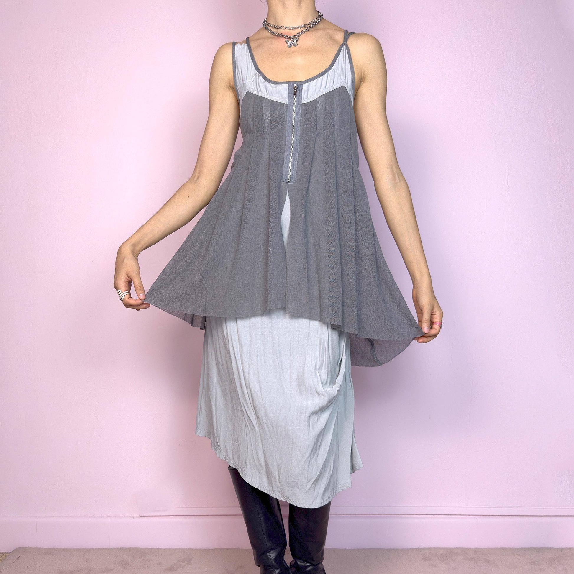 This vintage 2000s midi dress features layered grey tones in mixed textures, including a pleated mesh overlay with faux front zip detail and a side zipper closure. The sleeveless cut and flared asymmetric drape create sculptural movement. Falls below the knee, lightweight, with no stretch. A deconstructed Y2K silhouette—futuristic, quiet, and avant-garde. Perfect for summer days or experimental night looks. Excellent vintage condition.
