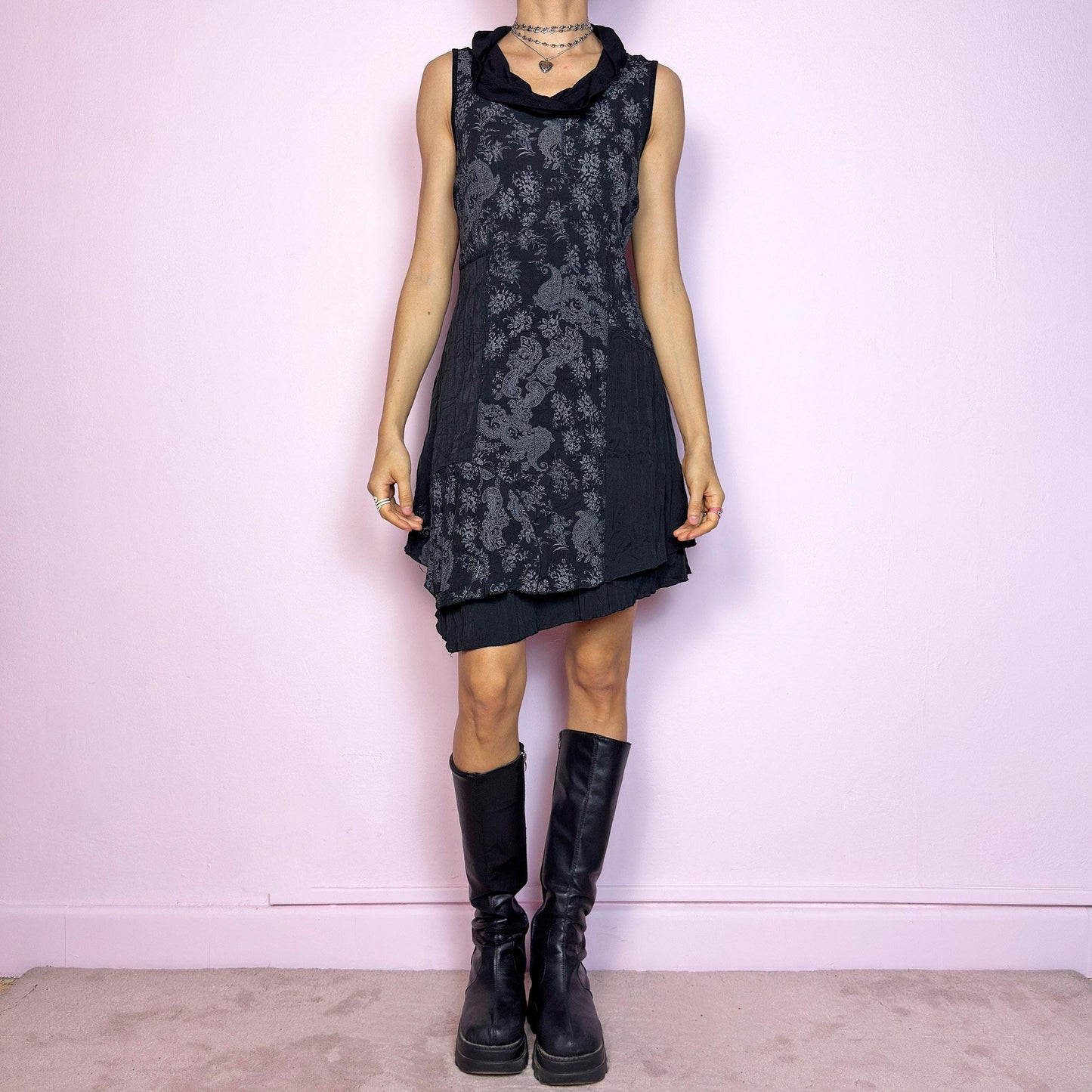The Y2K Black Asymmetric Mini Dress is a vintage 2000s dress featuring an elegant paisley print and a deconstructed layered design. The cowl neckline and sleeveless cut create a soft, fluid silhouette, while the asymmetric hem adds a playful edge. Made with slightly crinkled fabric, it offers a flattering A-line shape. Perfect for artsy, indie, or witchy Y2K-inspired looks. Great vintage condition.