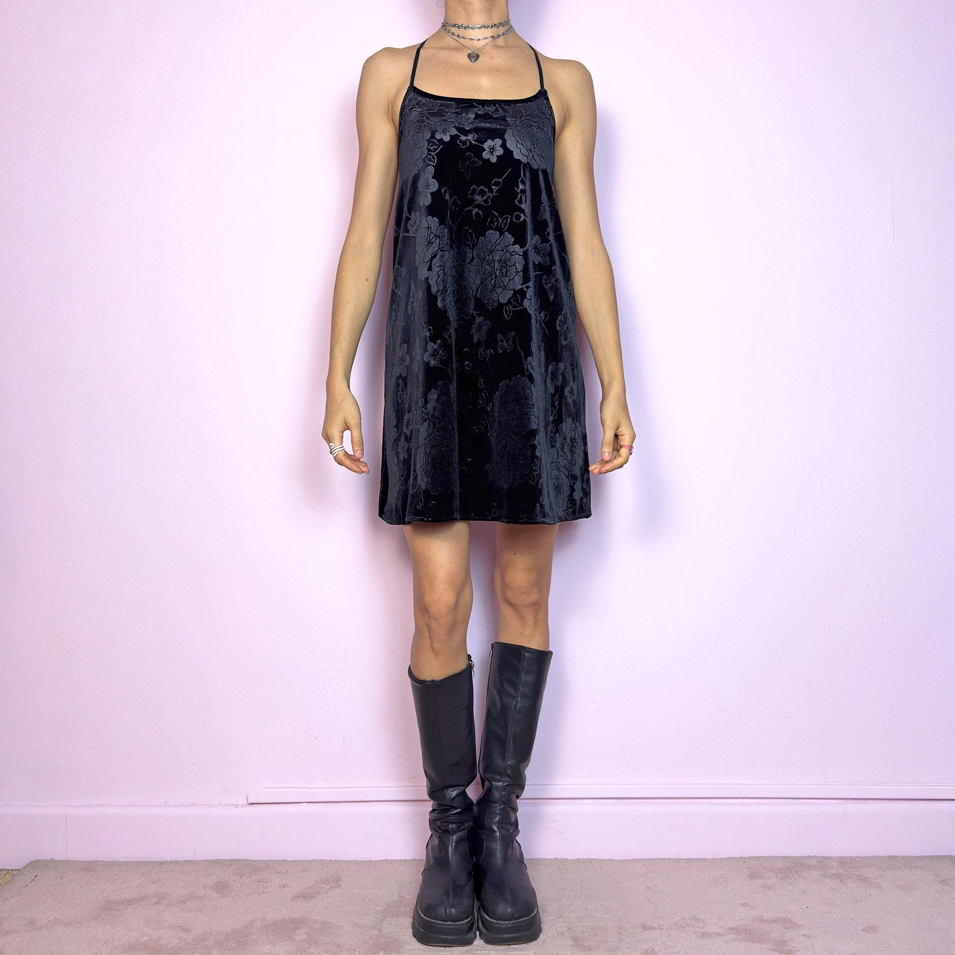 This vintage 2000s black mini dress is cut from floral burnout velvet with a soft sheen and dimensional texture. It features a scoop neckline, thin shoulder straps, and a dramatic open halter back. The A-line silhouette skims the body with fluid ease, offering stretch and light structure. Perfect for summer nights. A dark romantic piece with sleek sensuality and a touch of whimsical allure. Great vintage condition.