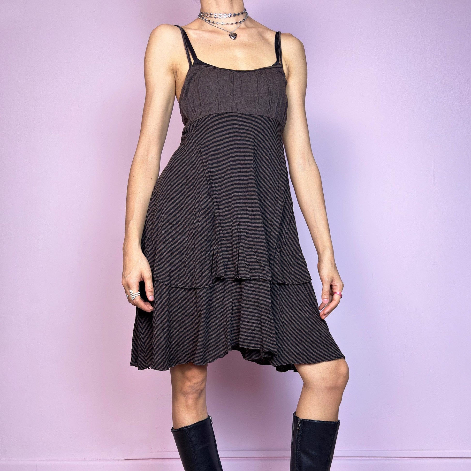 This vintage 2000s brown midi dress features a fine black stripe pattern, square neckline, and thin shoulder straps. Made from a soft, stretchy knit, it has an empire waist and a tiered asymmetric hem that drapes with ease. Perfect for summer. A casual, fairy grunge–inspired piece with subtle volume and flow—blending comfort, minimalism, and quiet edge. Great vintage condition.