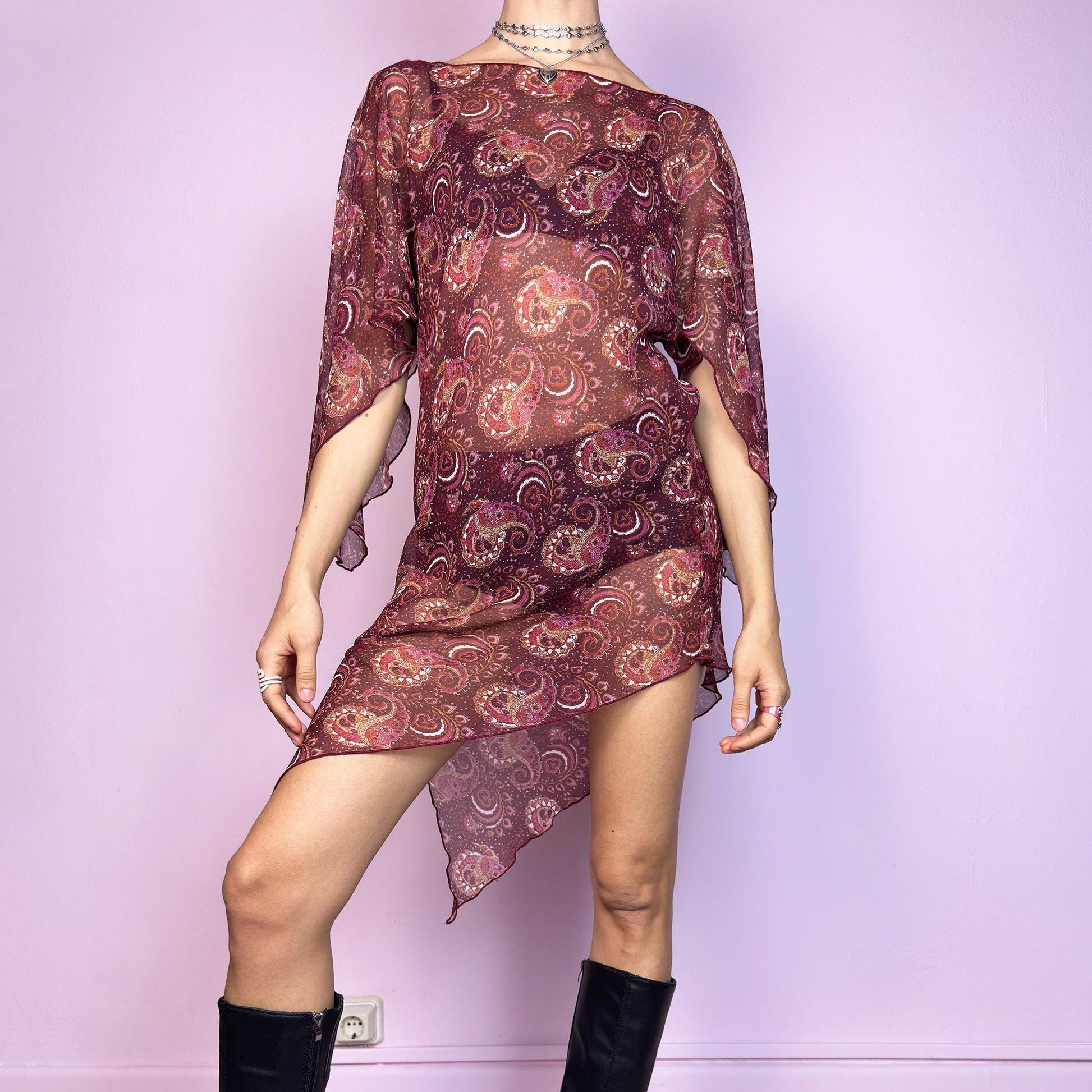 This vintage 2000s mini dress features a sheer burgundy paisley print, wide butterfly sleeves, and an asymmetric hem. Cut from lightweight fabric with no stretch, it drapes fluidly and falls mid-thigh with high side slits. Unlined and semi-transparent, perfect for layering or worn bold. A romantic Y2K silhouette with bohemian and fairycore energy—effortless, floaty, and made for summer nights. Great vintage condition.