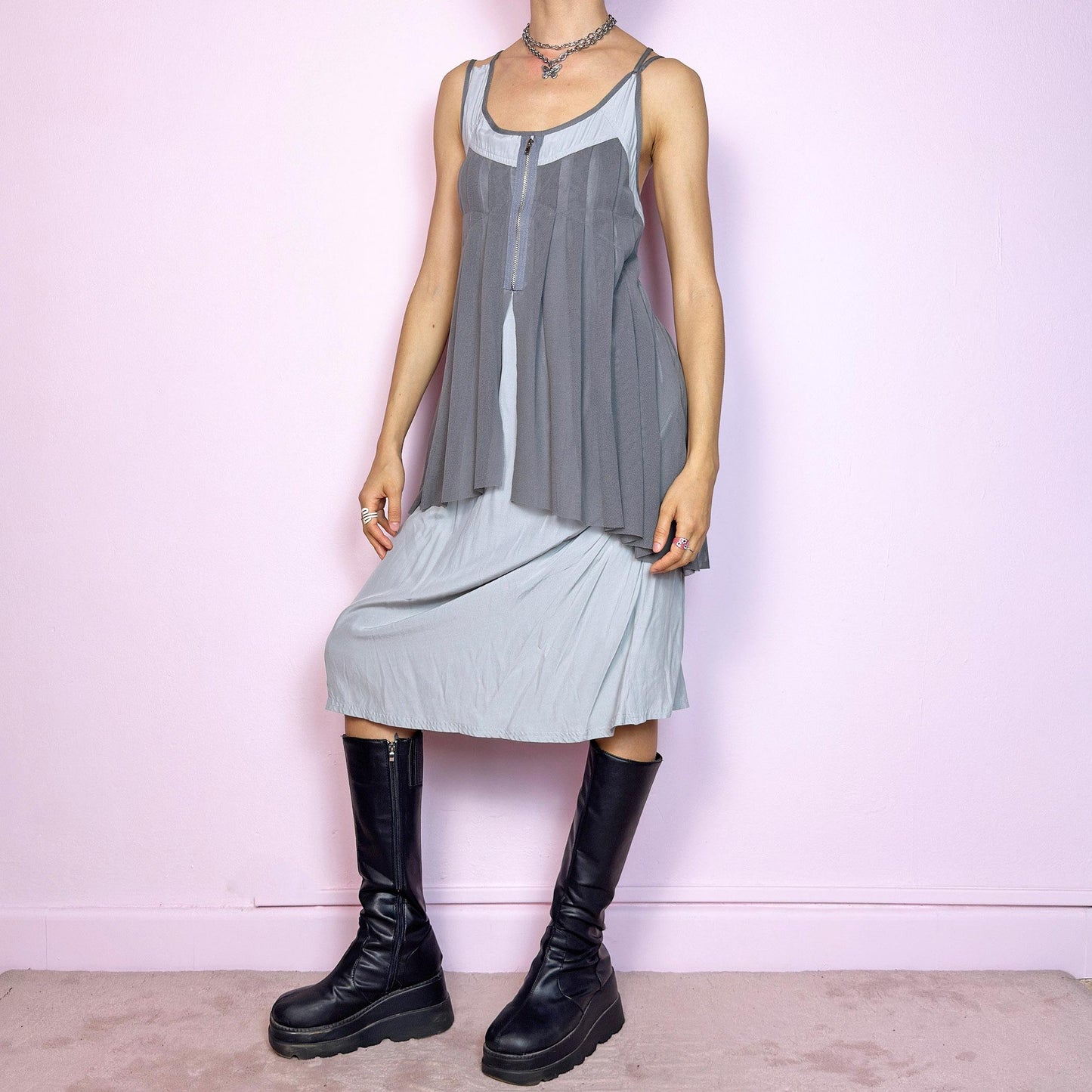 This vintage 2000s midi dress features layered grey tones in mixed textures, including a pleated mesh overlay with faux front zip detail and a side zipper closure. The sleeveless cut and flared asymmetric drape create sculptural movement. Falls below the knee, lightweight, with no stretch. A deconstructed Y2K silhouette—futuristic, quiet, and avant-garde. Perfect for summer days or experimental night looks. Excellent vintage condition.