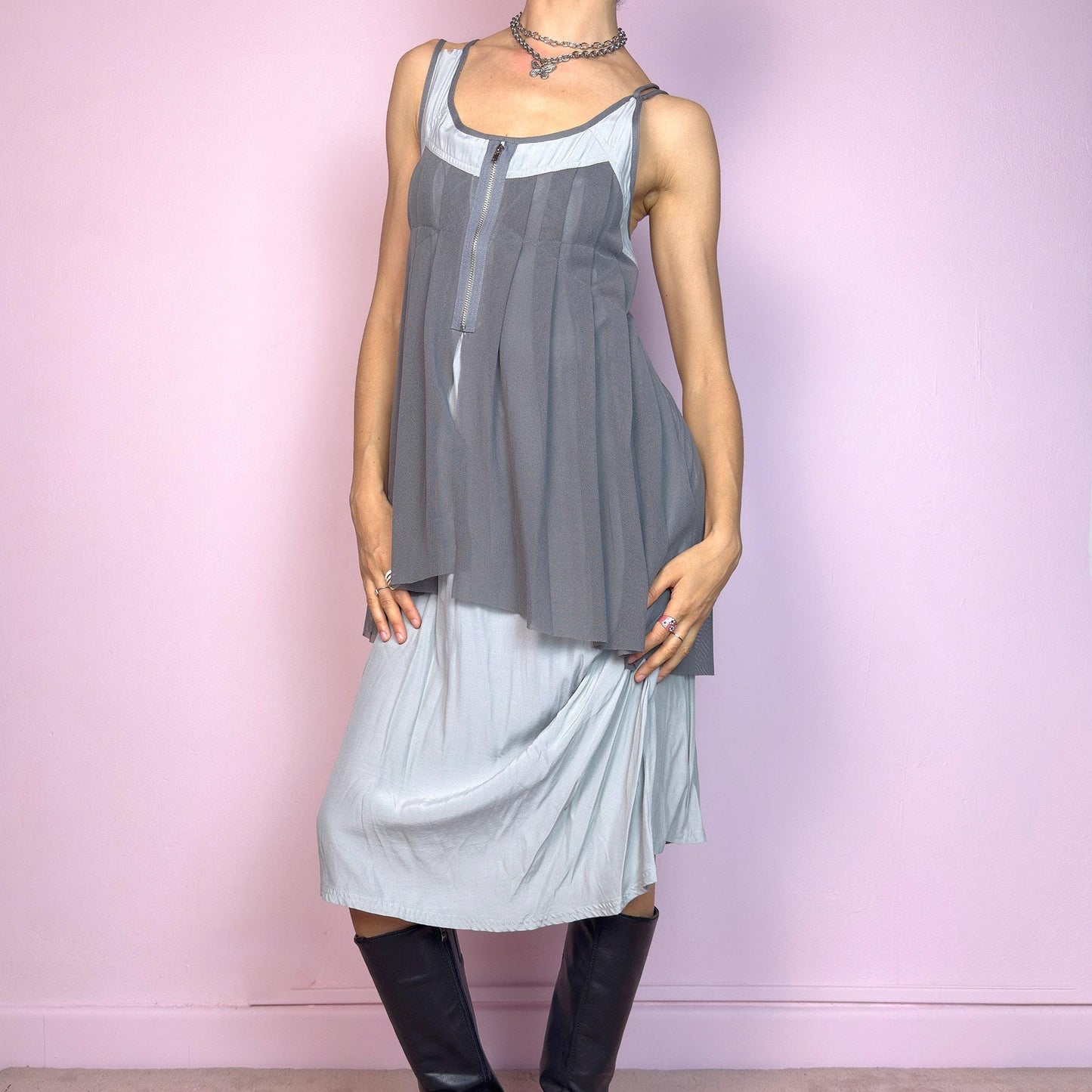 This vintage 2000s midi dress features layered grey tones in mixed textures, including a pleated mesh overlay with faux front zip detail and a side zipper closure. The sleeveless cut and flared asymmetric drape create sculptural movement. Falls below the knee, lightweight, with no stretch. A deconstructed Y2K silhouette—futuristic, quiet, and avant-garde. Perfect for summer days or experimental night looks. Excellent vintage condition.
