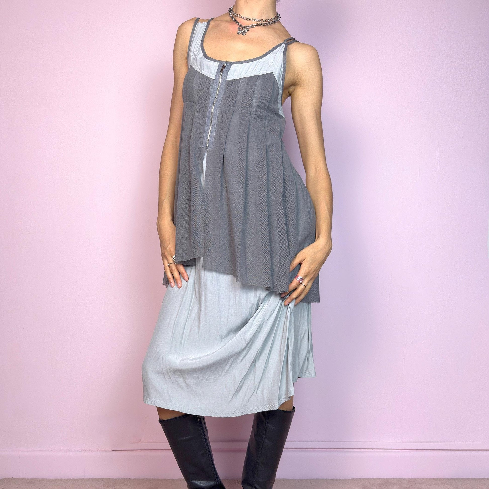 This vintage 2000s midi dress features layered grey tones in mixed textures, including a pleated mesh overlay with faux front zip detail and a side zipper closure. The sleeveless cut and flared asymmetric drape create sculptural movement. Falls below the knee, lightweight, with no stretch. A deconstructed Y2K silhouette—futuristic, quiet, and avant-garde. Perfect for summer days or experimental night looks. Excellent vintage condition.