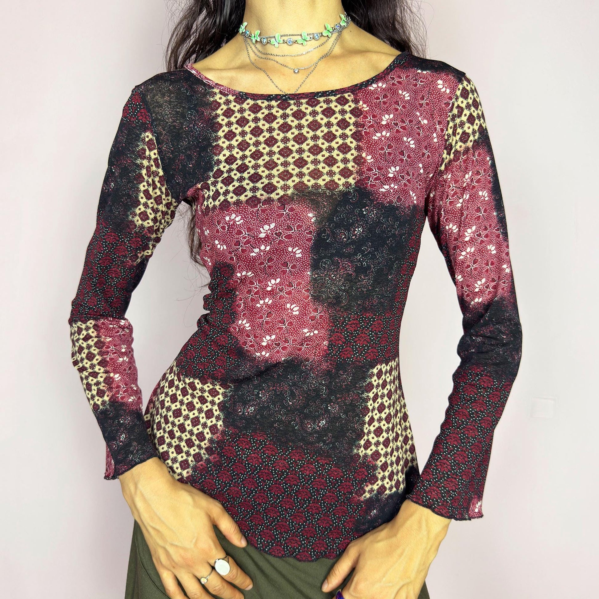 This vintage 2000s mesh top features bracelet-length bell sleeves and a patchwork floral print in burgundy, black, and beige tones. The fitted silhouette and lettuce hem add delicate structure to its ethereal mood. Ideal for witchy autumn layering or spring evening parties. A romantic, whimsical Y2K piece. Made of stretch polyester. Excellent vintage condition.