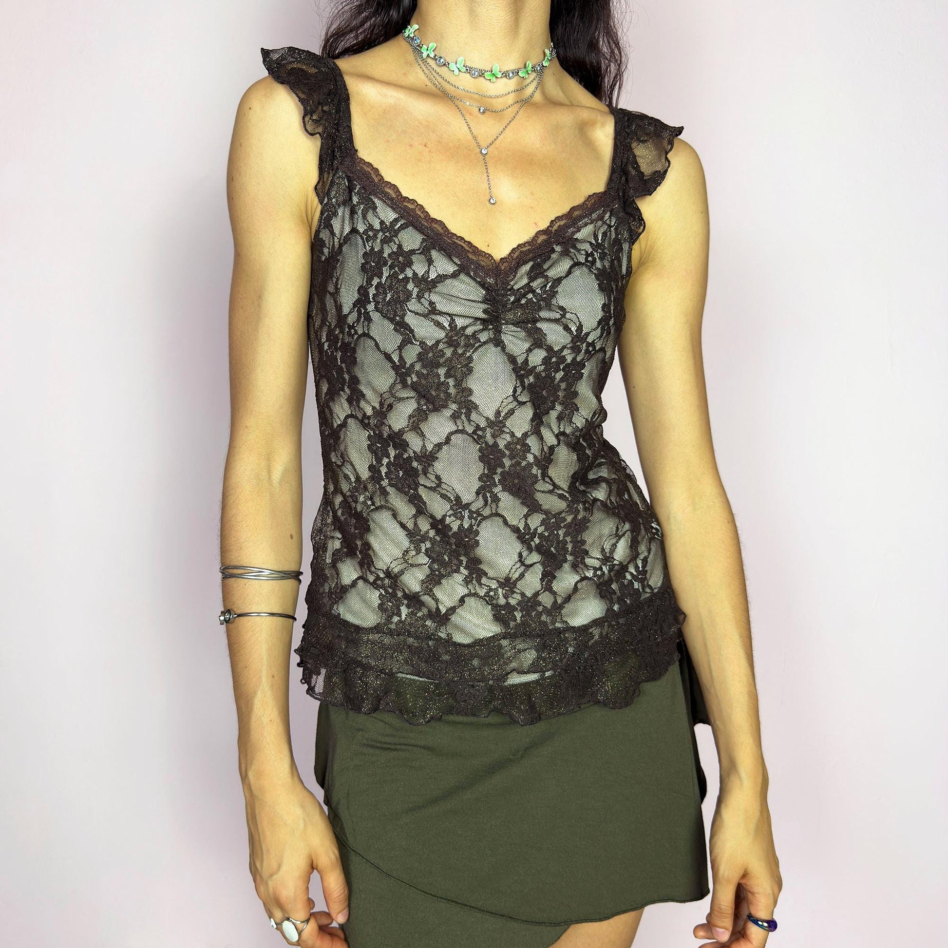 This vintage 2000s brown mesh cami top features delicate floral lace, ruched bust detail, and soft ruffle straps. The sheer, stretchy fit flatters with romantic allure, ideal for enchanting first dates, summer evening parties, or layered boho looks. A whimsical, charming, and sensual Y2K piece. Made of stretch polyester mesh. Excellent vintage condition.