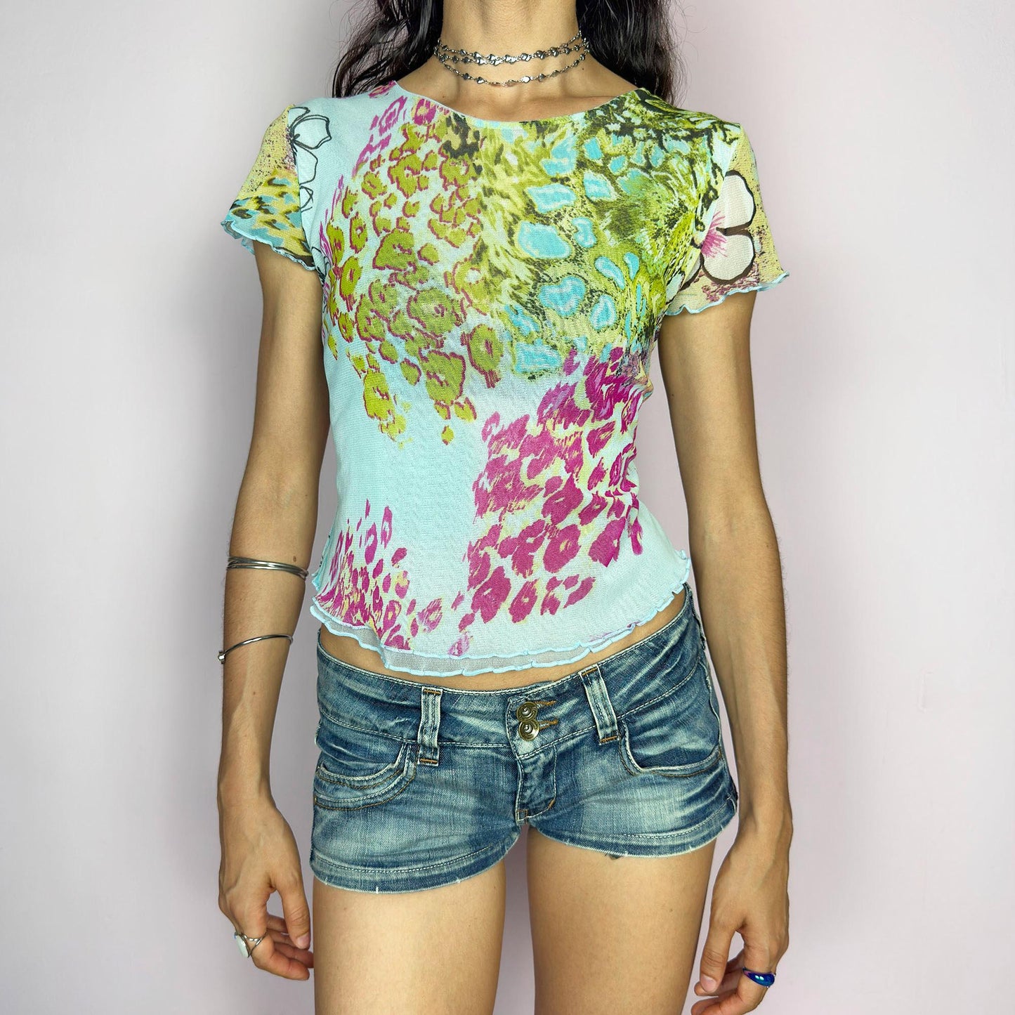 This vintage 2000s soft semi-sheer mesh tee bursts with pastel animal prints in pistachio, aqua, pink, and fuchsia over a baby blue base. The graphic collage is finished with delicate lettuce edging at the sleeves and hem. Perfect for summer festivals, casual layering, or a sunny day ice cream outing. A super cute, collectible Y2K piece with sweet attitude. Made of stretch polyester mesh from a French brand. Excellent vintage condition.