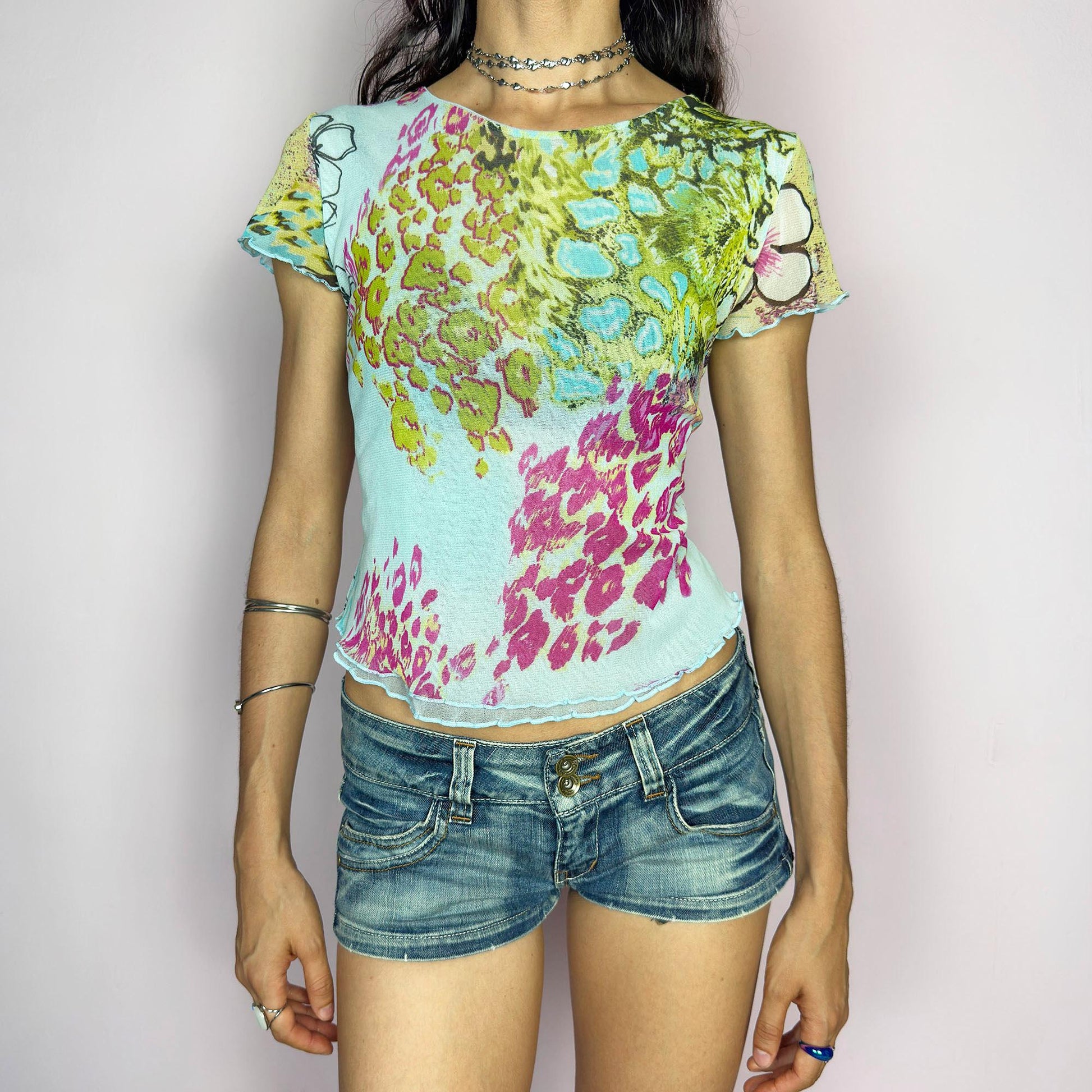 This vintage 2000s soft semi-sheer mesh tee bursts with pastel animal prints in pistachio, aqua, pink, and fuchsia over a baby blue base. The graphic collage is finished with delicate lettuce edging at the sleeves and hem. Perfect for summer festivals, casual layering, or a sunny day ice cream outing. A super cute, collectible Y2K piece with sweet attitude. Made of stretch polyester mesh from a French brand. Excellent vintage condition.