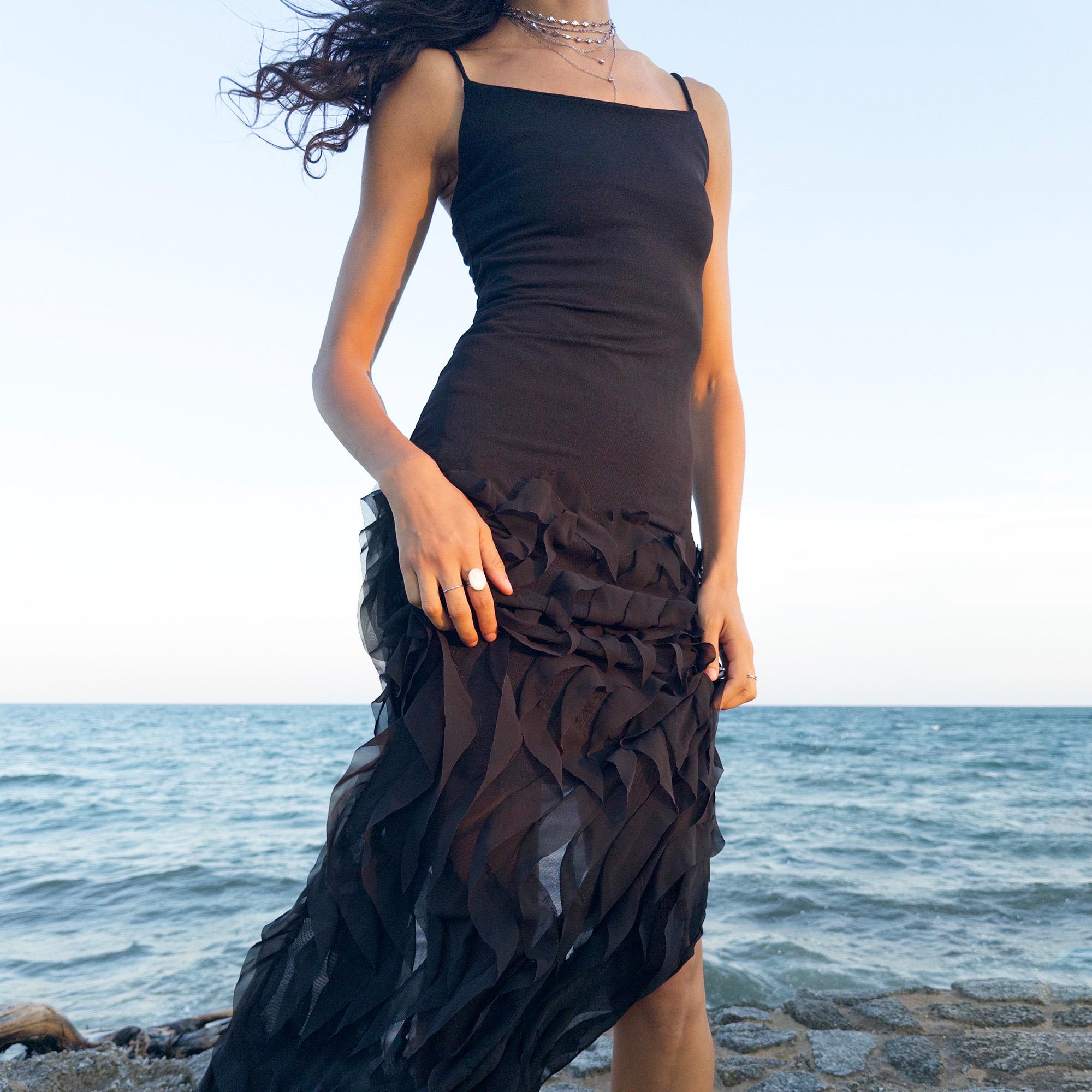The vintage 90s black mesh midi dress is a sculptural piece with sheer wave appliqué layered across the skirt, minimalist neckline, and a back slit for fluidity. Its body-skimming silhouette fuses quiet sensuality with architectural edge. Ideal for city nights, gallery parties, or modern cocktail looks. An avant garde archive find made in the USA from a stretchy polyester blend. Excellent vintage condition.