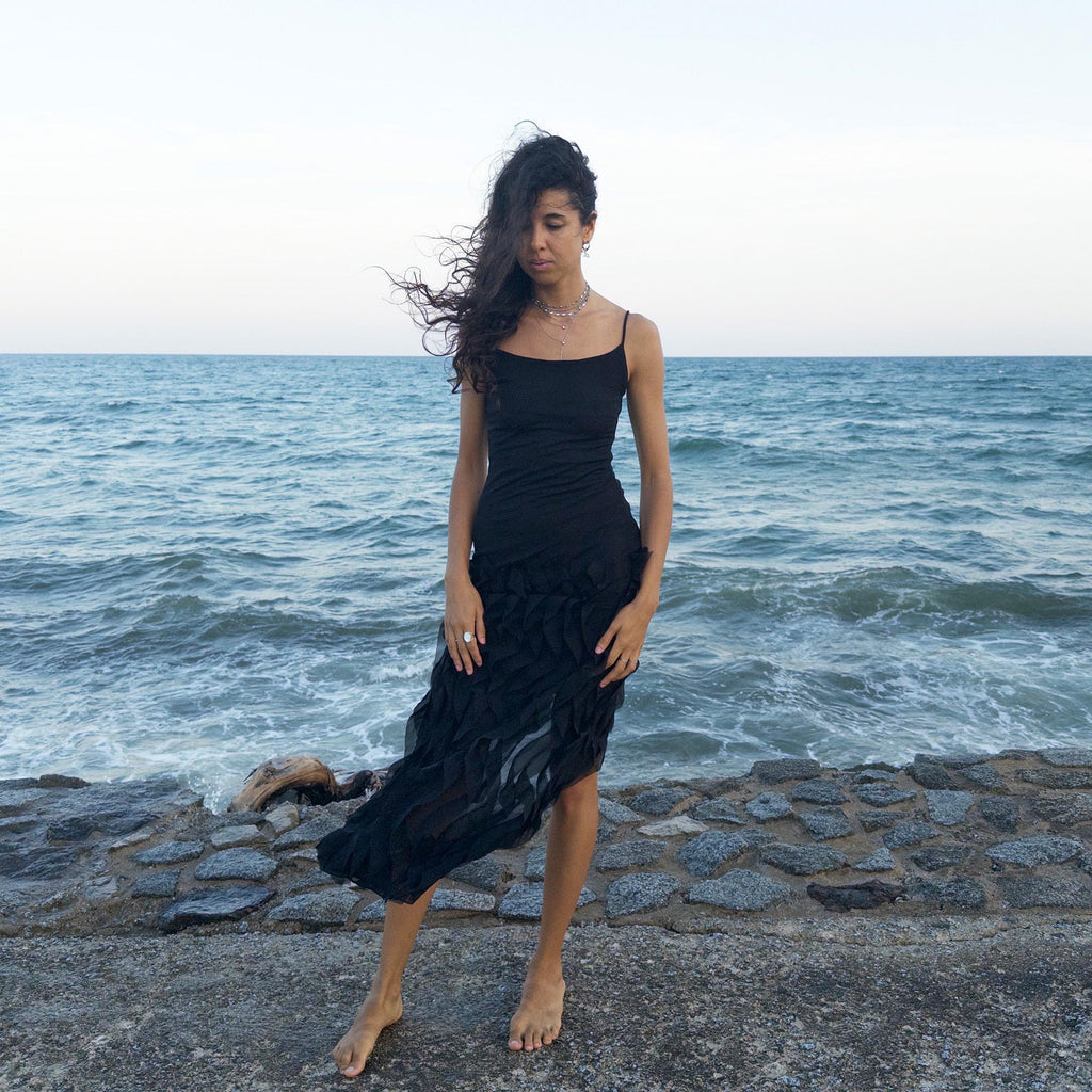The vintage 90s black mesh midi dress is a sculptural piece with sheer wave appliqué layered across the skirt, minimalist neckline, and a back slit for fluidity. Its body-skimming silhouette fuses quiet sensuality with architectural edge. Ideal for city nights, gallery parties, or modern cocktail looks. An avant garde archive find made in the USA from a stretchy polyester blend. Excellent vintage condition.