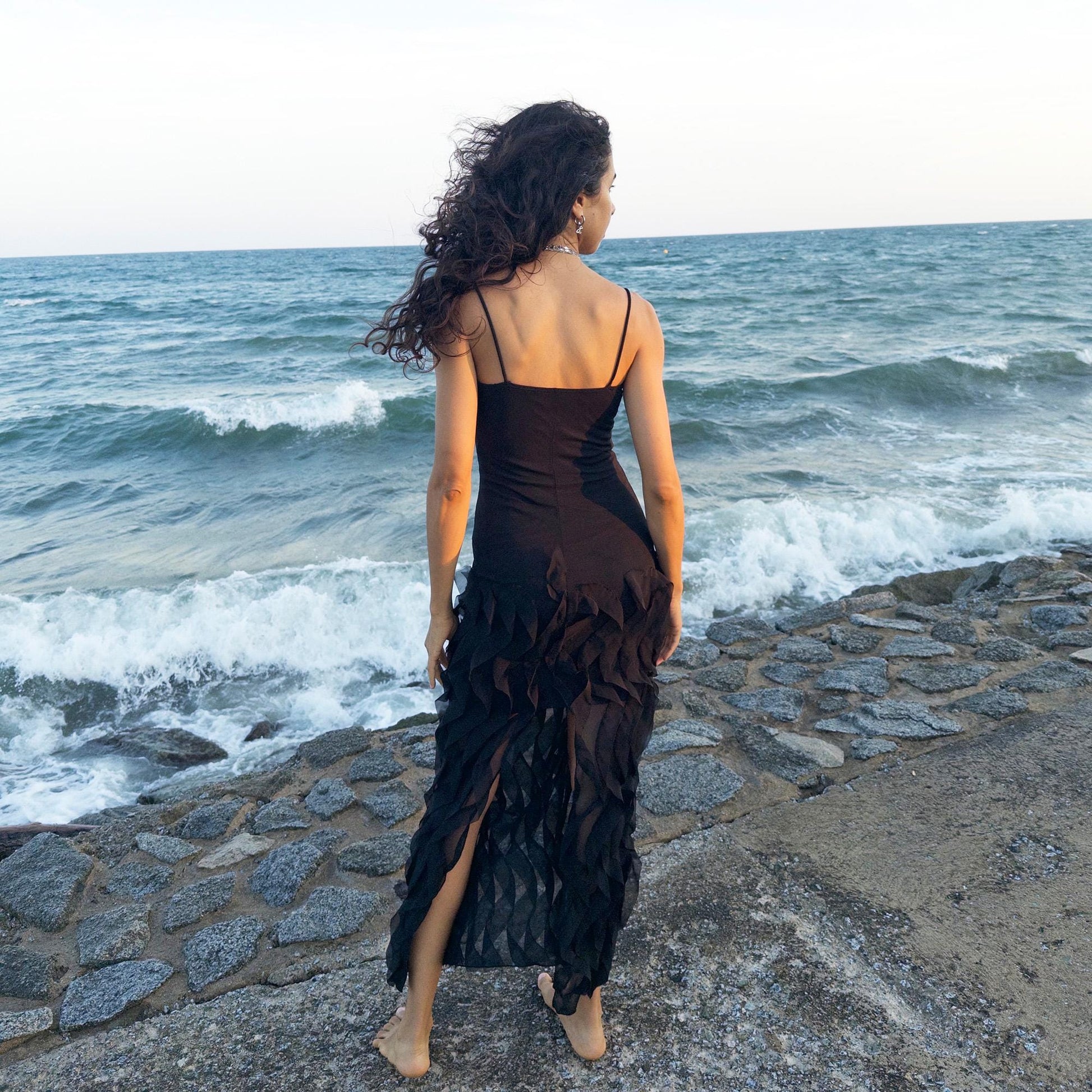 The vintage 90s black mesh midi dress is a sculptural piece with sheer wave appliqué layered across the skirt, minimalist neckline, and a back slit for fluidity. Its body-skimming silhouette fuses quiet sensuality with architectural edge. Ideal for city nights, gallery parties, or modern cocktail looks. An avant garde archive find made in the USA from a stretchy polyester blend. Excellent vintage condition.