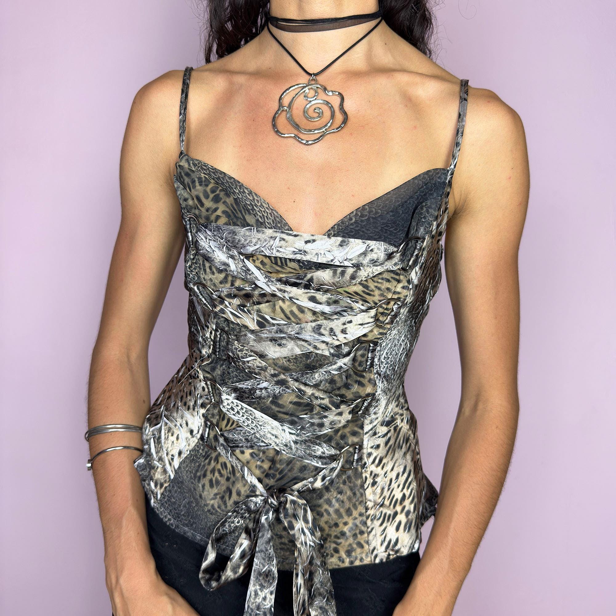 The Y2K Animal Print Corset Top is a vintage 2000s piece with a bold leopard and reptile mix print, lace-up tie front, and sculpted corset-style bodice. Featuring slim spaghetti straps and a hidden side zipper closure, this structured sleeveless top hugs the body with fierce elegance. Perfect for red carpet-inspired nights, festival glam, or a diva statement look that channels fearless Y2K energy with sensual edge. Excellent vintage condition.