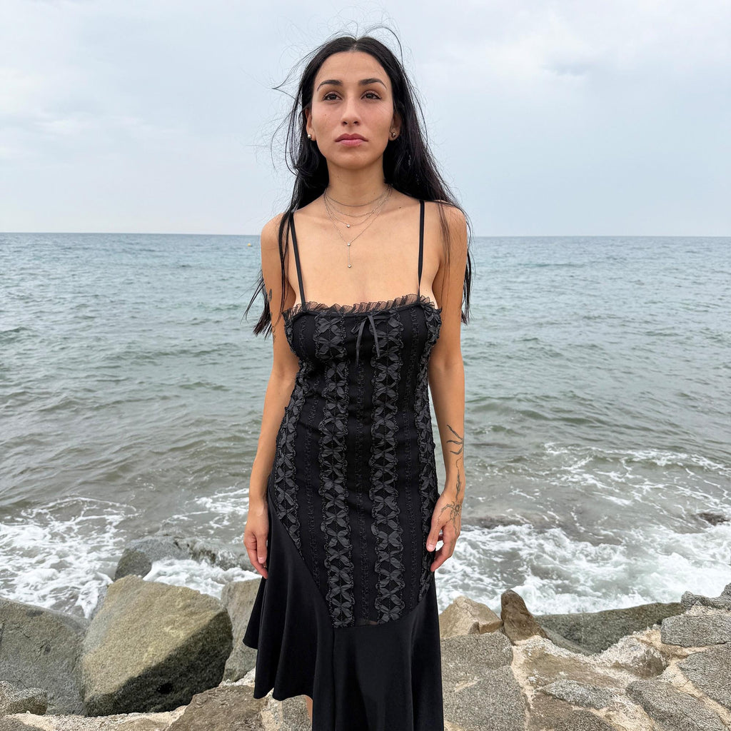 This vintage 2000s black midi dress features an asymmetrical handkerchief hem with whimsical flow and delicate mesh panel details through the bodice. Crafted in France from a stretchy polyester blend, it hugs the figure while allowing movement. A romantic dark piece with fairy, witchy, and night-party energy—perfect for Y2K alternative styling. Made from polyester stretch blend. Excellent vintage condition.